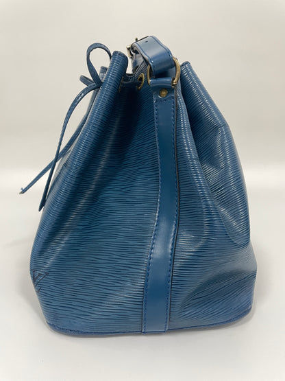 Left side of Louis Vuitton Petit Noé Shoulder Bag in Toledo Blue Leather, highlighting the smooth texture and leather strap.