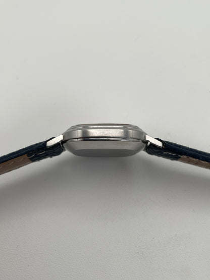 Side view of Omega 591.0016 vintage quartz watch with an oval-shaped silver case, slim profile, and blue leather strap.