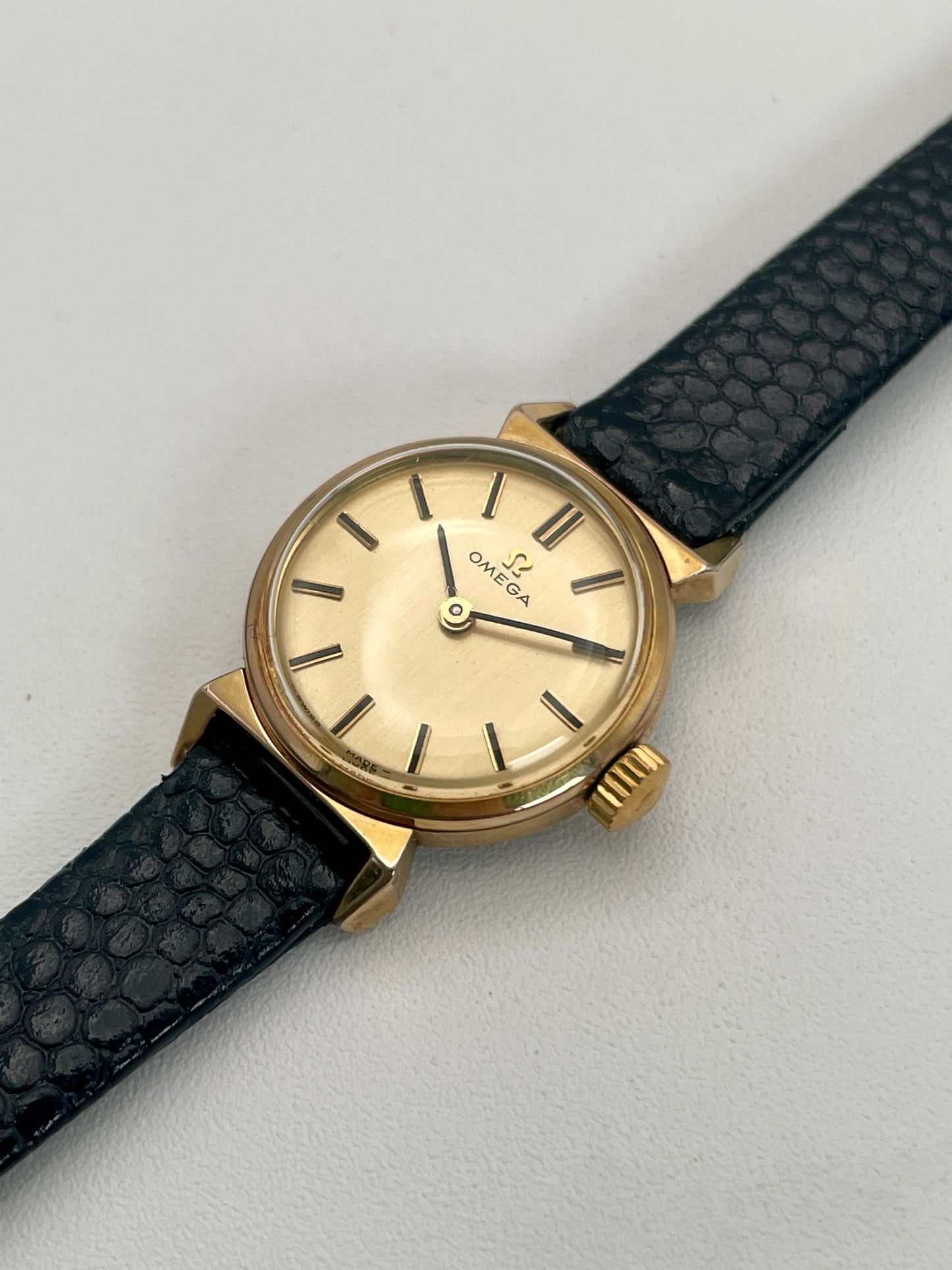 Diagonal view of Omega Art Deco gold vintage ladies watch with black leather strap.