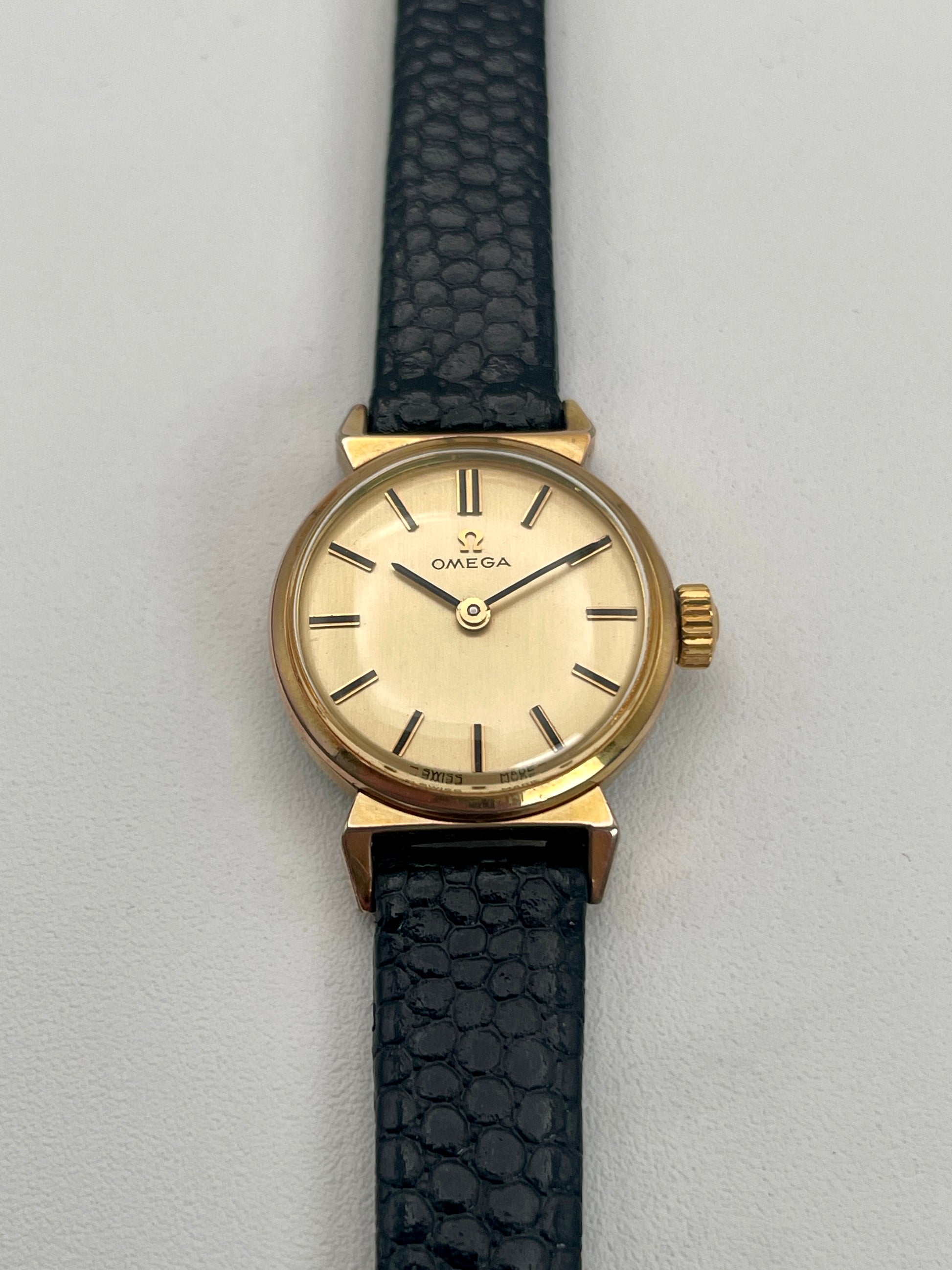 Front view of Omega Art Deco ladies watch in gold featuring a minimalist champagne dial.