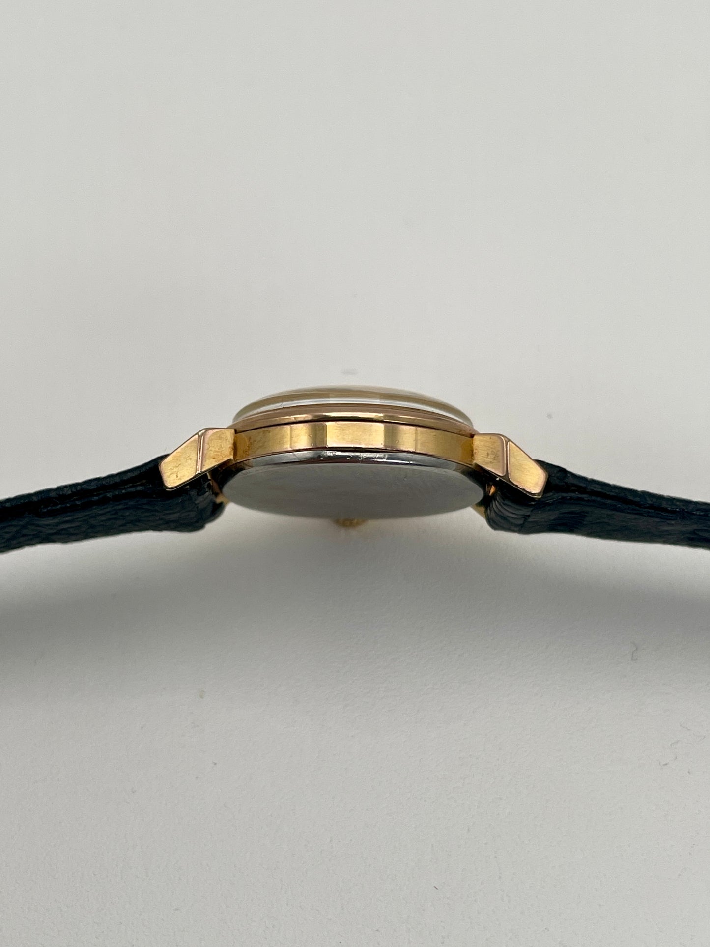 Side profile of Omega Art Deco vintage gold ladies watch with elegant black strap.