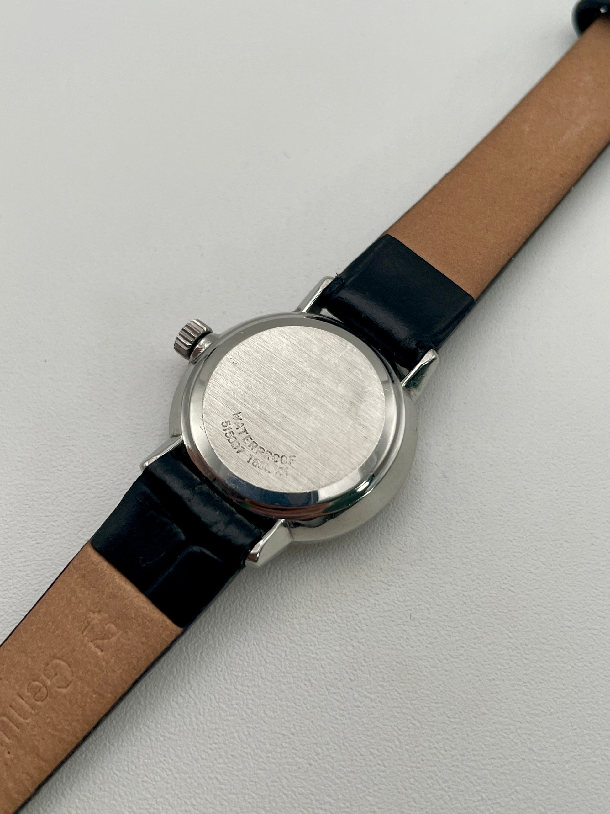 Caseback view of the Omega De Ville 515.007 vintage women's watch, featuring a stainless steel back and black leather strap.