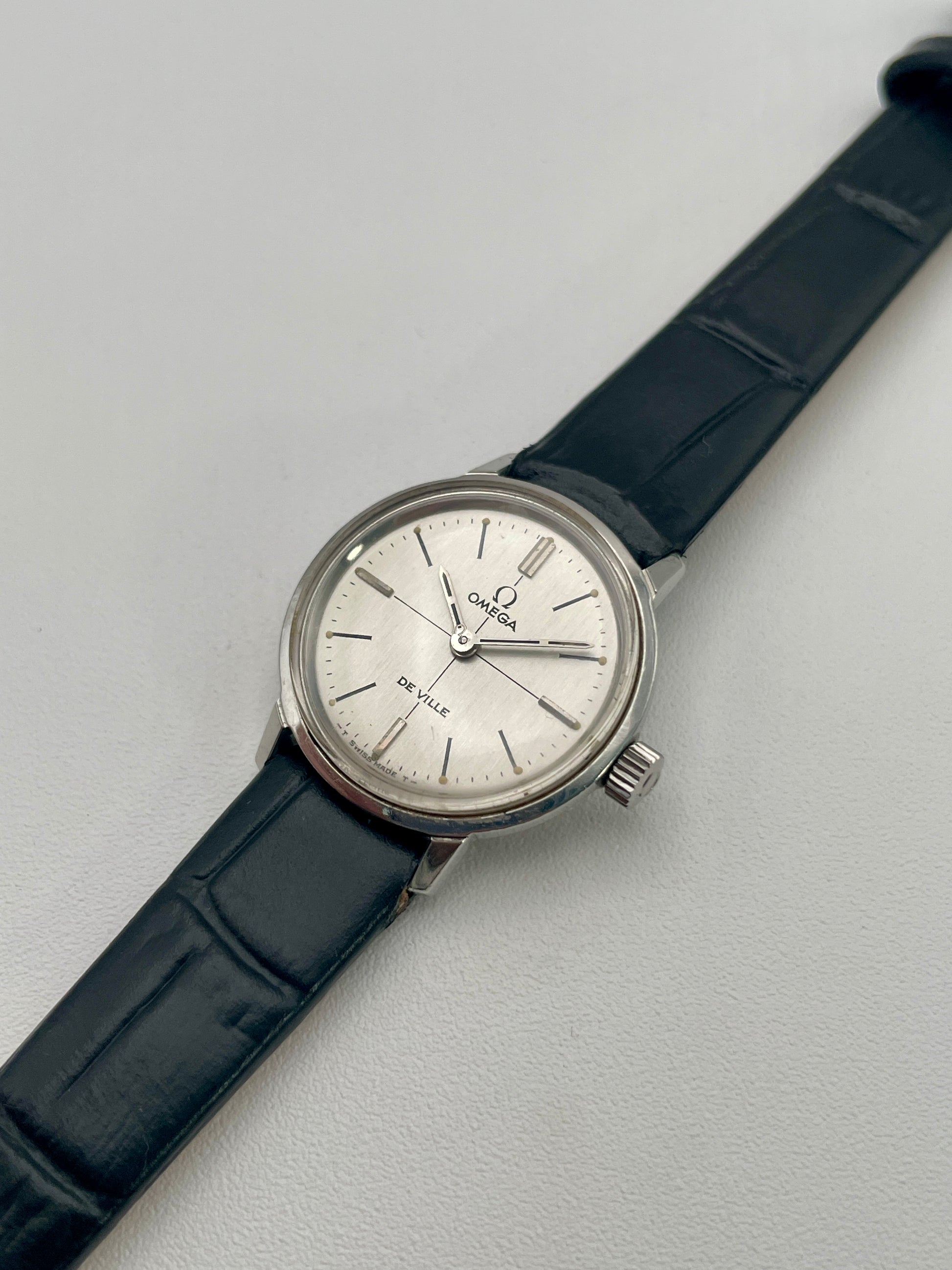 Angled view of the Omega De Ville 515.007 vintage watch highlighting its polished stainless steel case and elegant silver sunburst dial.