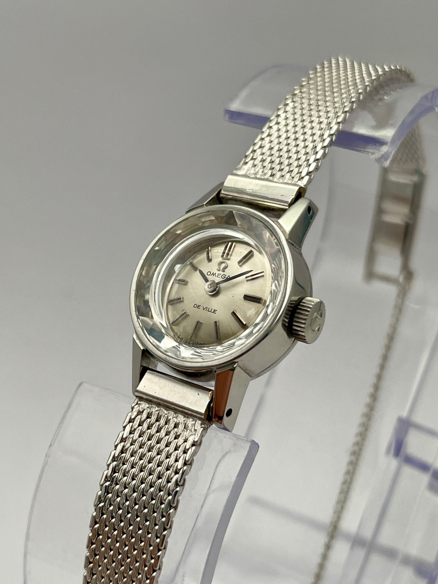 Diagonal view of the Omega De Ville watch with cut glass crystal, highlighting the stainless steel case and silver dial