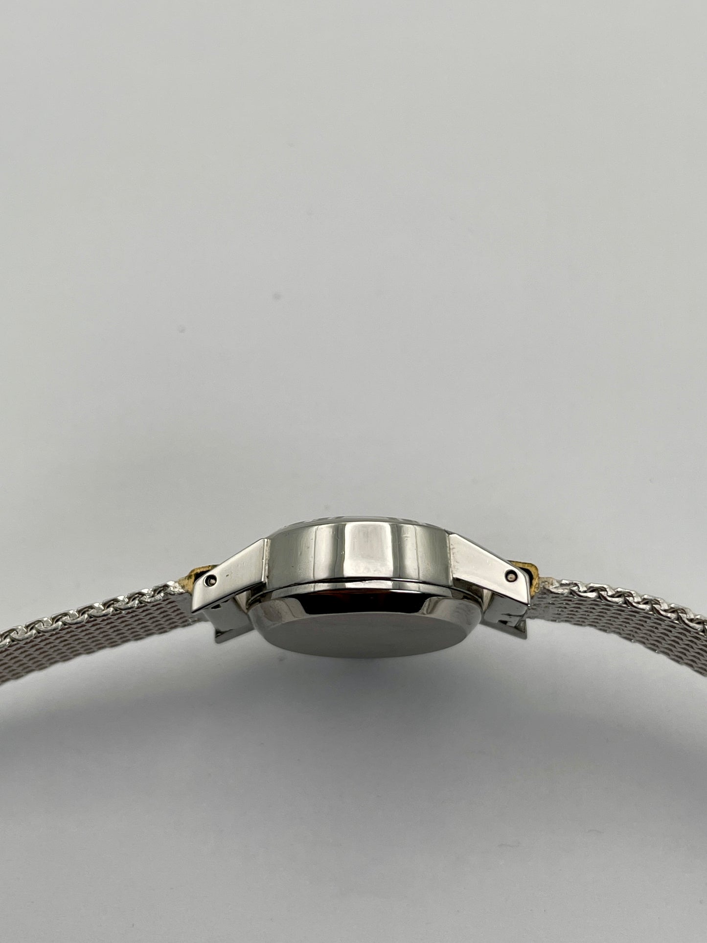 Side view of the Omega De Ville watch, showcasing stainless steel case and mesh bracelet