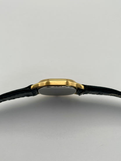 Side case view of Omega De Ville vintage gold watch with a slim gold case and black leather strap.