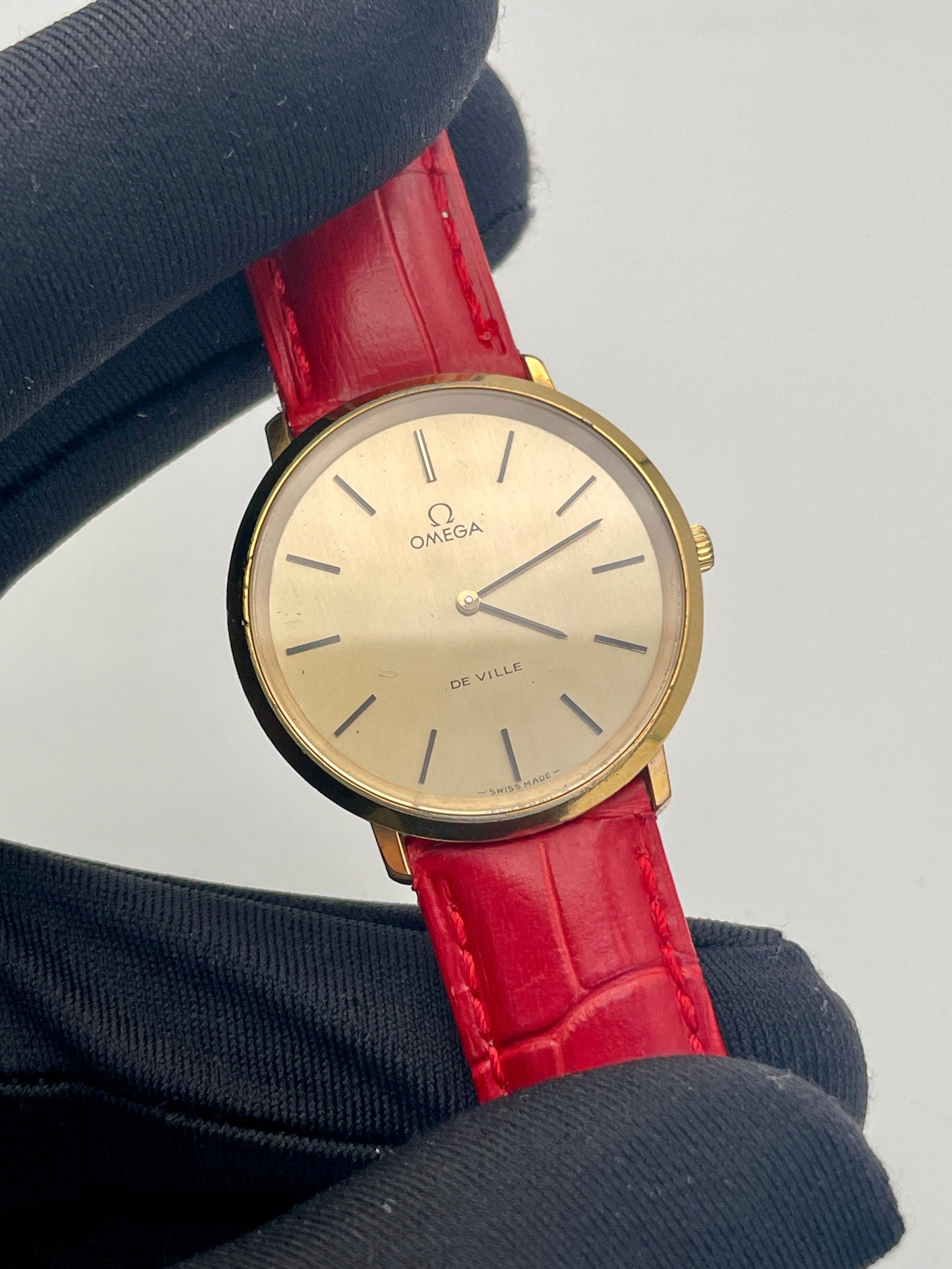 Omega De Ville Ref. 111.0144 gold watch with red strap, close-up view.