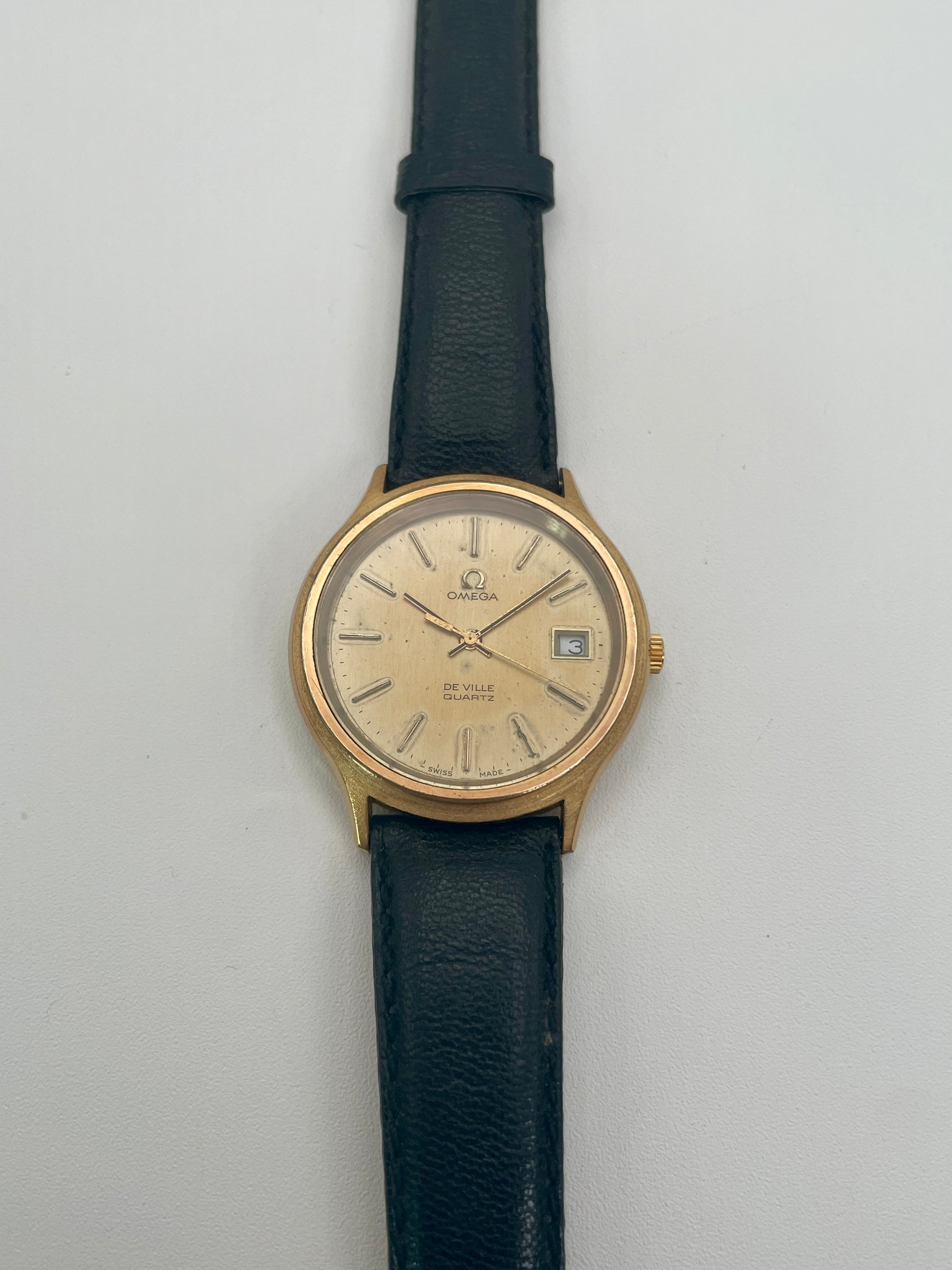 Omega De Ville 192.0033 vintage watch in gold with black strap, front face view

