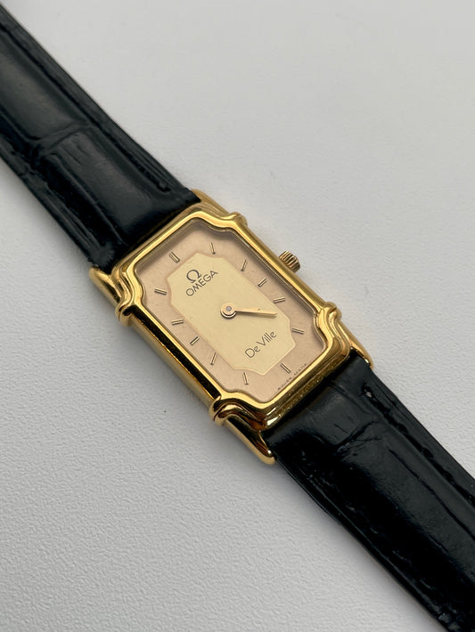 Front view of the Omega De Ville "Challenge" watch with an Art Deco style gold case and black leather strap, featuring a sector two-tone rectangular dial.