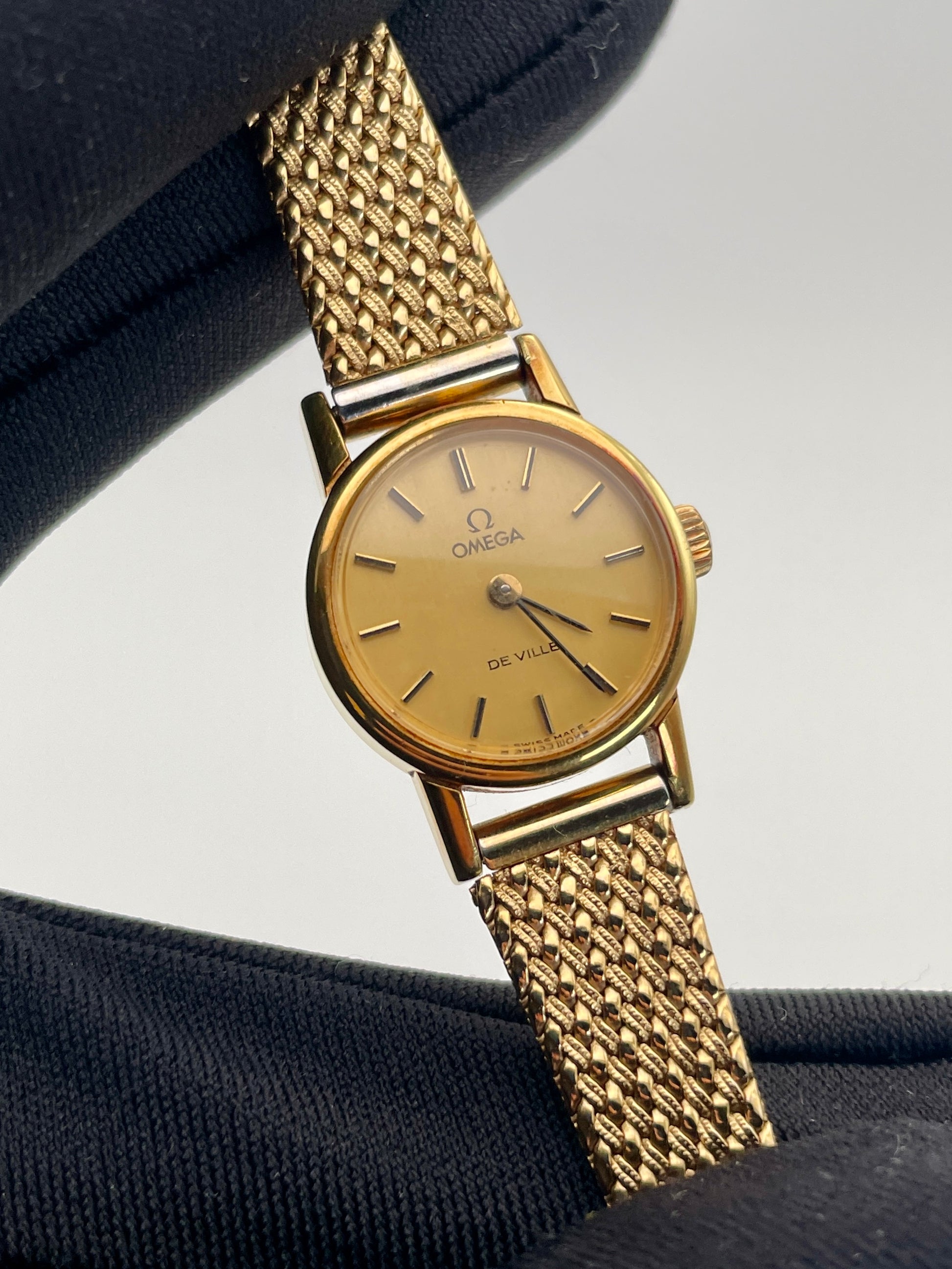 Close-up view of the vintage Omega De Ville ladies watch in gold with mesh bracelet.