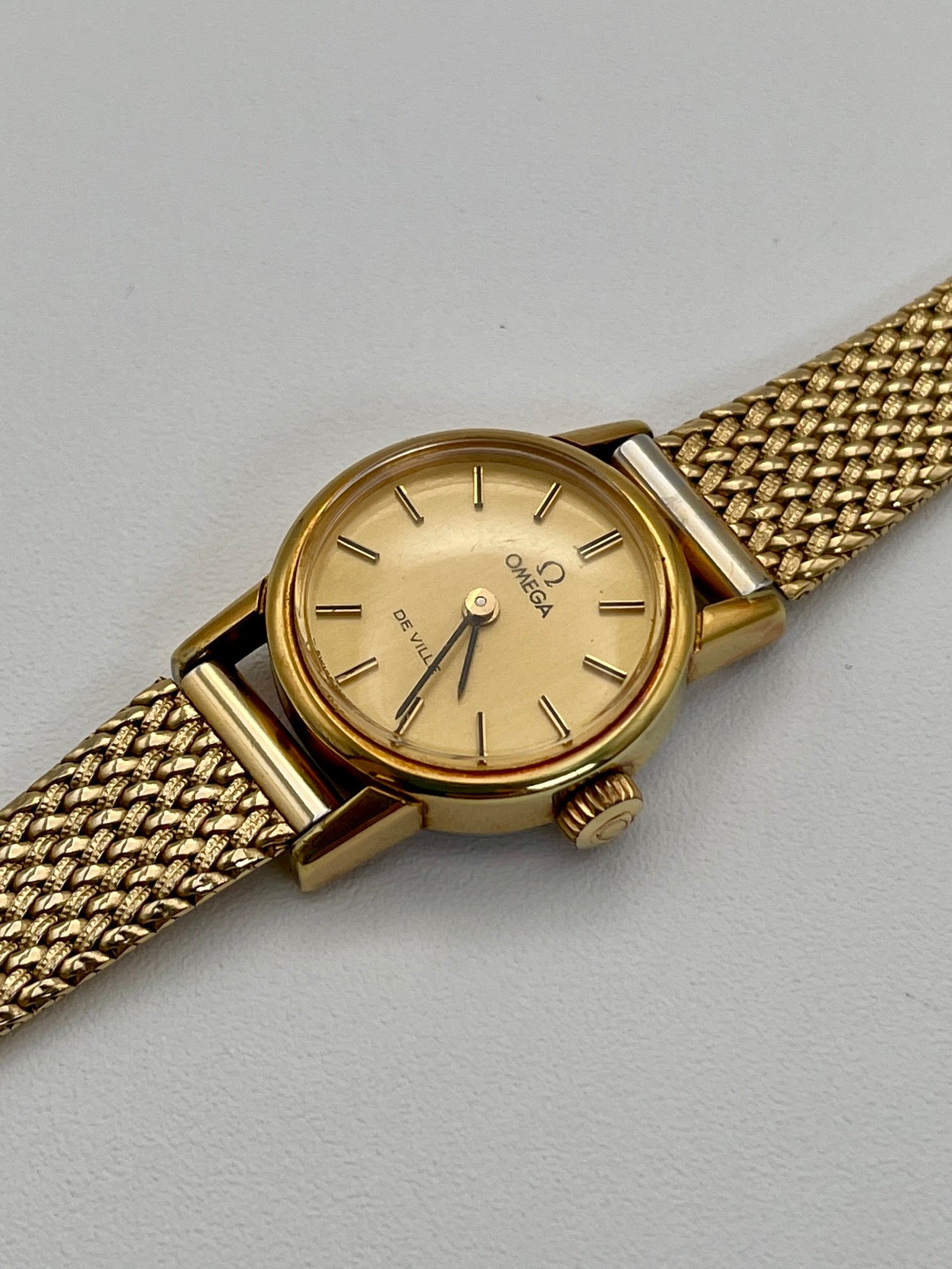 Diagonal view of the vintage Omega De Ville ladies watch in gold with mesh bracelet.