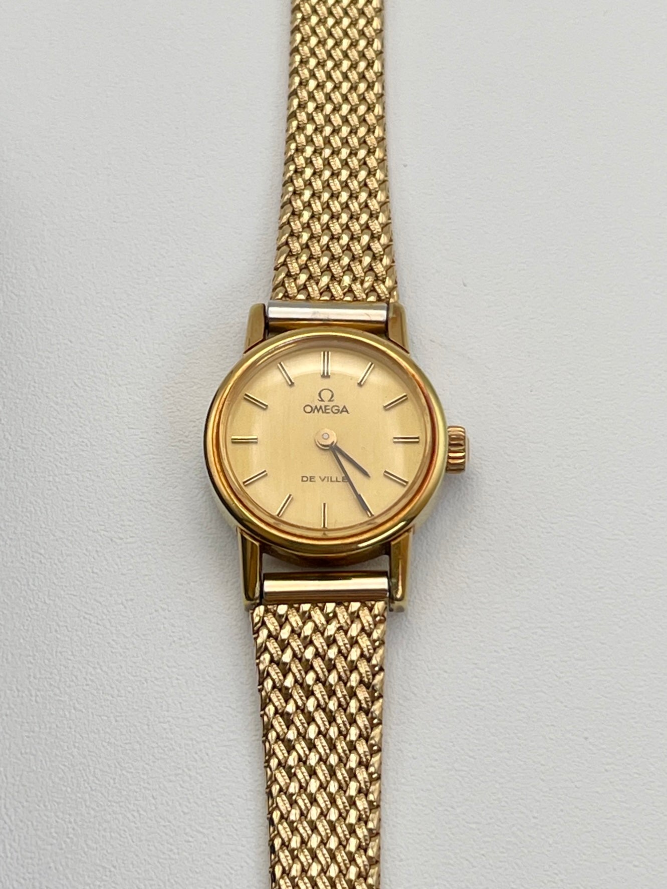 Front view of Vintage Omega De Ville ladies watch in gold with mesh bracelet.