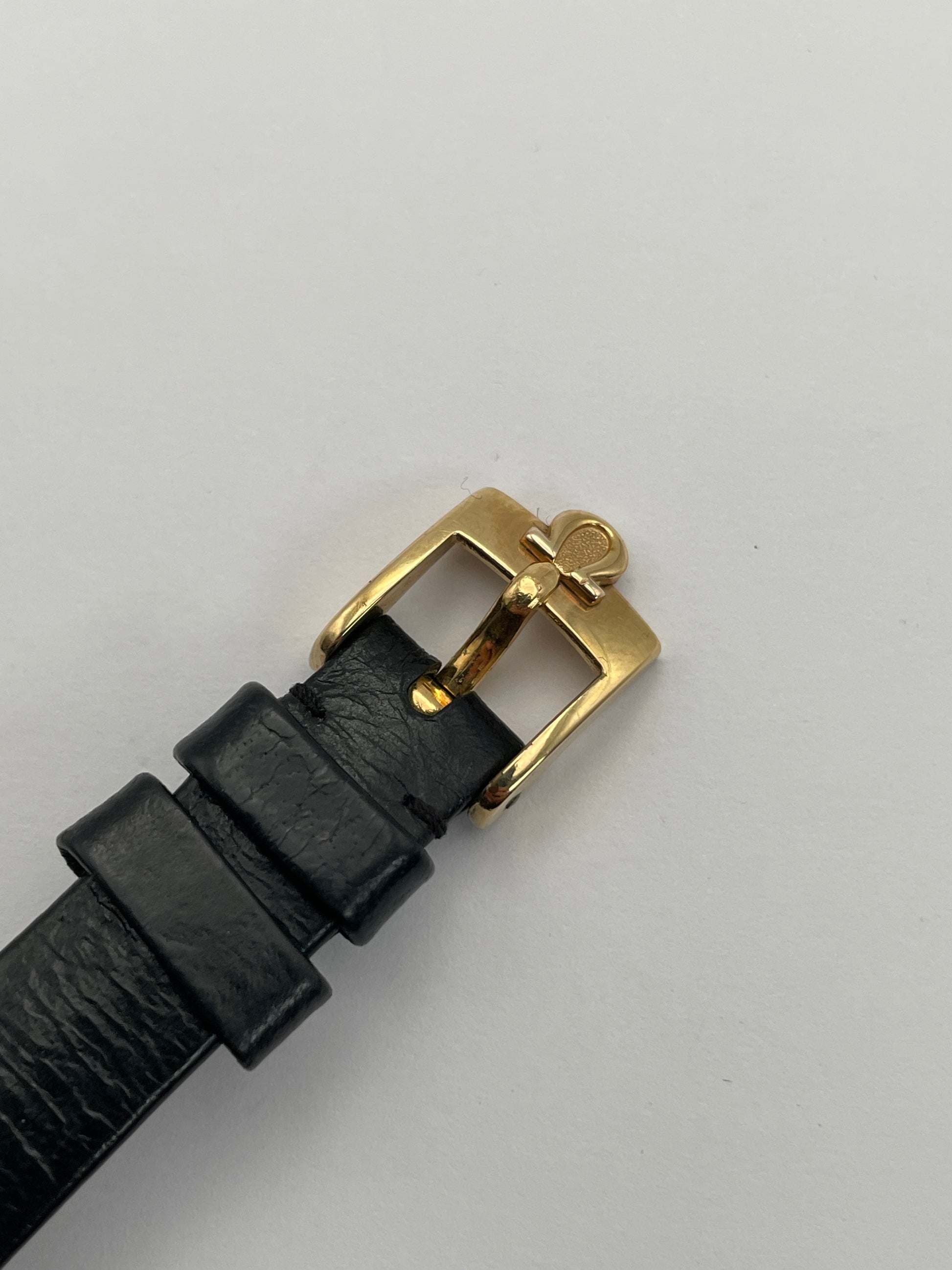 Close-up view of Omega De Ville TV Dial watch buckle with black leather strap.