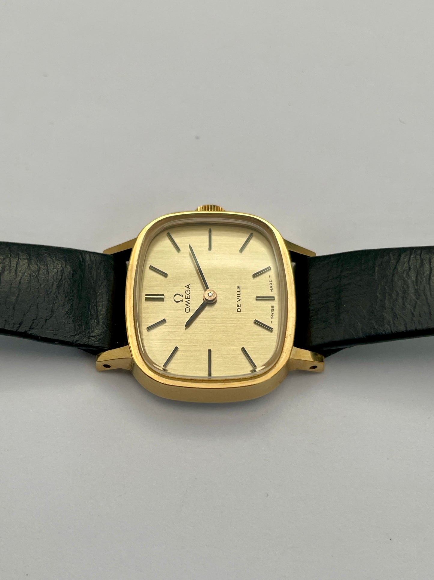 Top side view of Omega De Ville TV Dial watch highlighting the gold-tone square case and black leather strap.