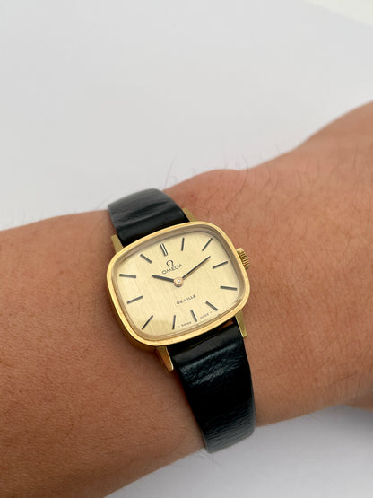 Omega De Ville TV Dial watch worn on wrist, featuring gold-tone square case and black leather strap.