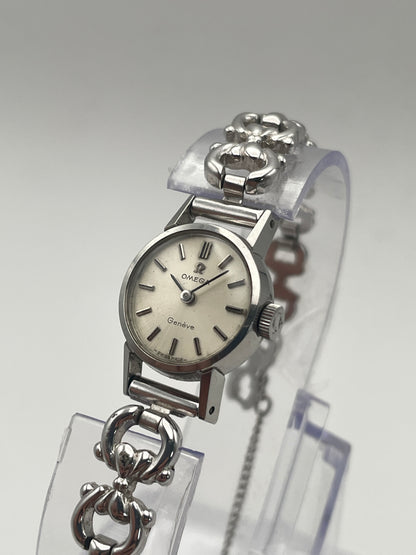 Diagonal view of Omega Genève ladies watch in silver-tone with a round case, silver dial, and intricate bracelet.