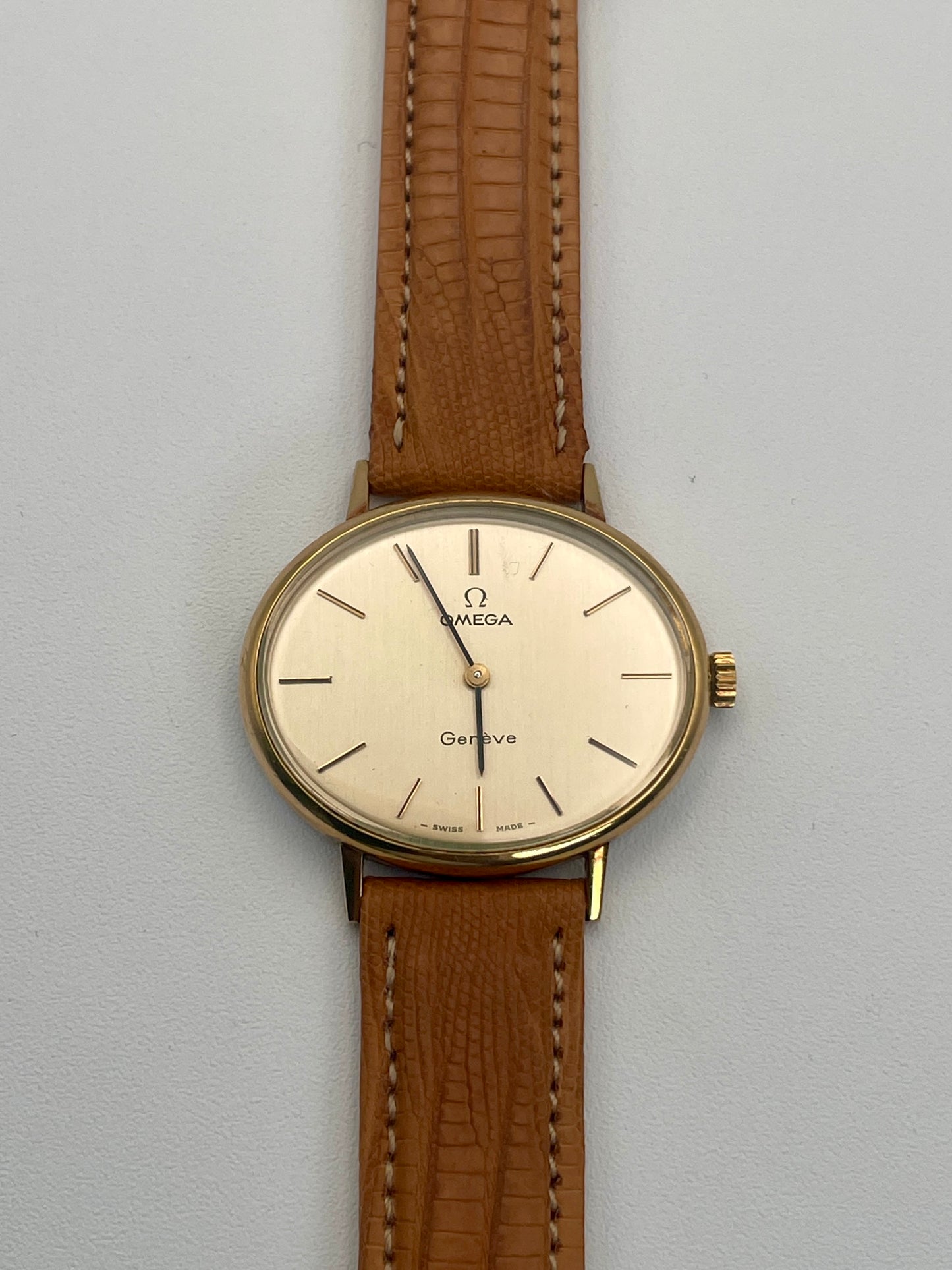 Front view of Omega Genève Ladies Watch with oval gold case and tan leather strap.