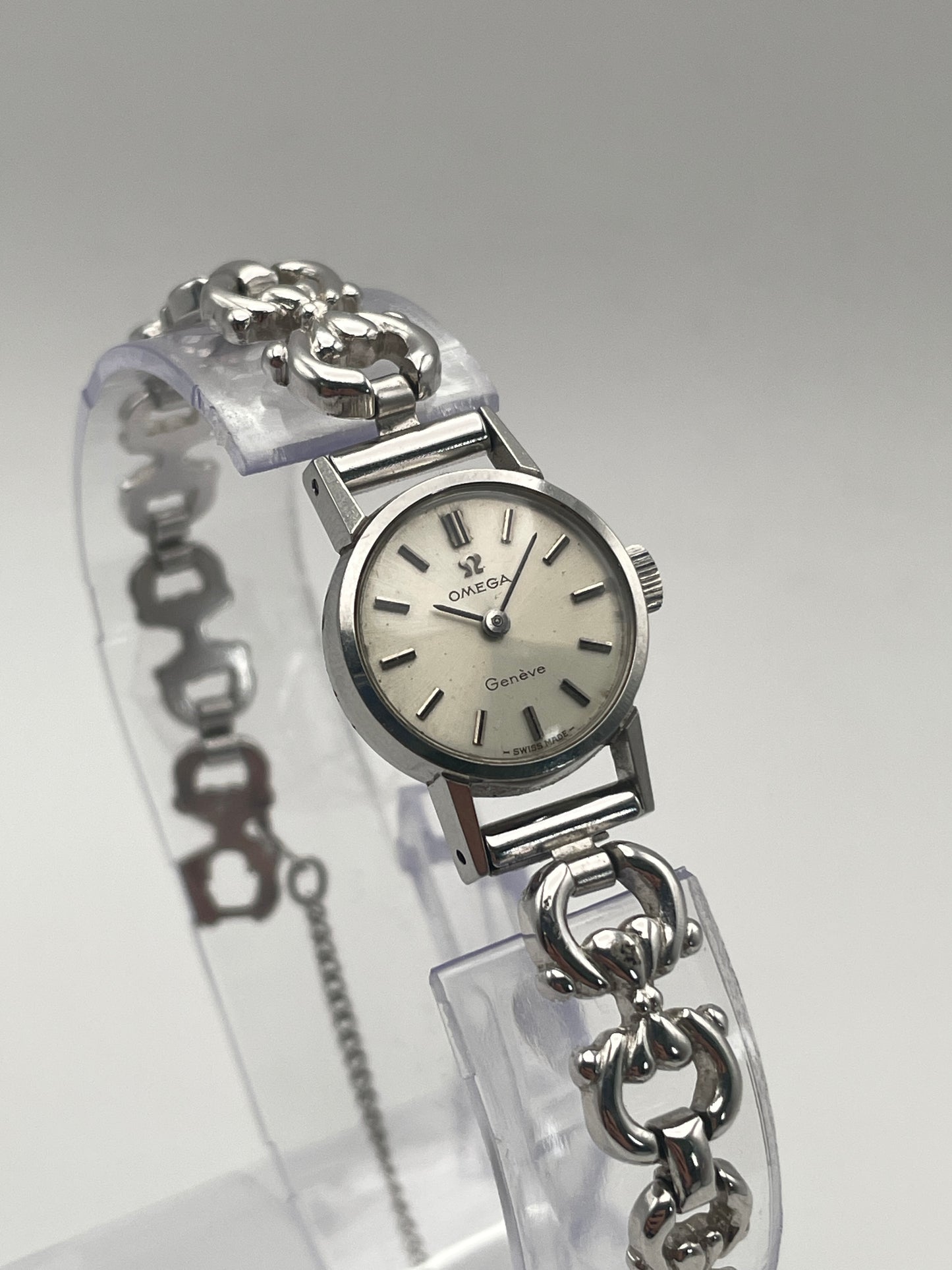 Omega Genève ladies watch in silver-tone with a round case, silver dial, and intricate bracelet.