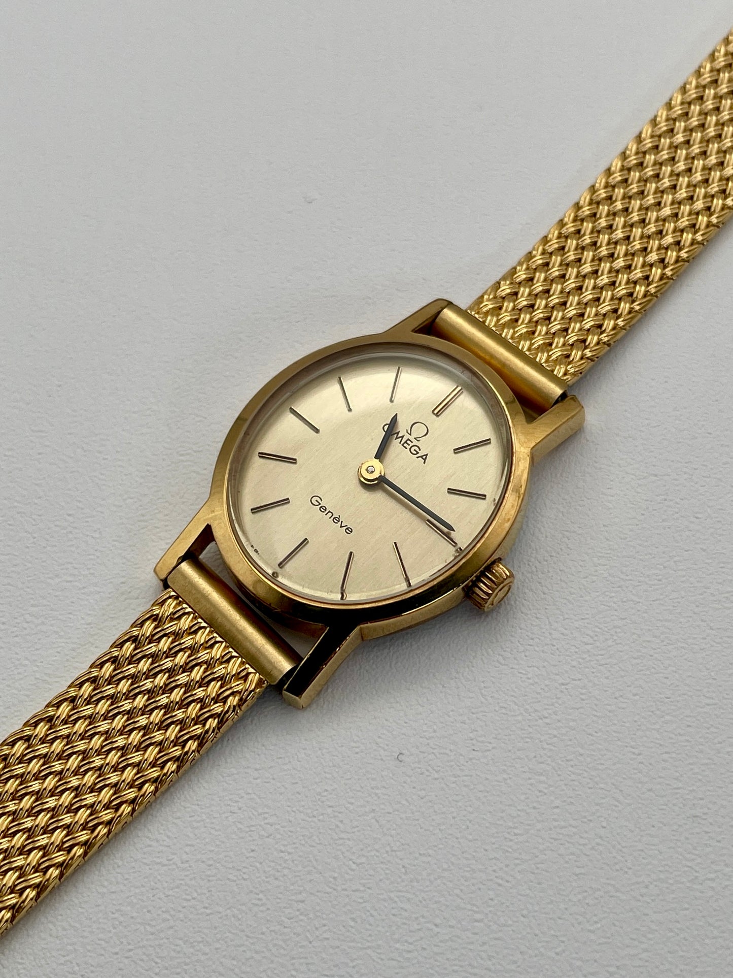 Omega Genève oval ladies watch in gold with a mesh bracelet, full front view.
