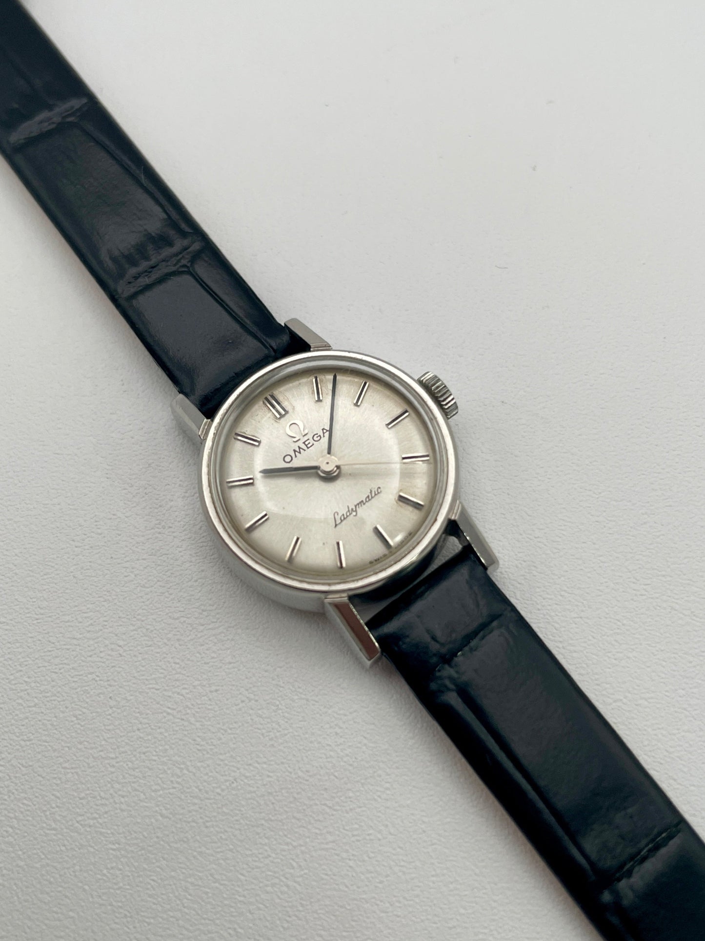 Front view of the Omega Ladymatic Vintage Women's Watch in Steel with a silver sunburst dial and black leather strap.