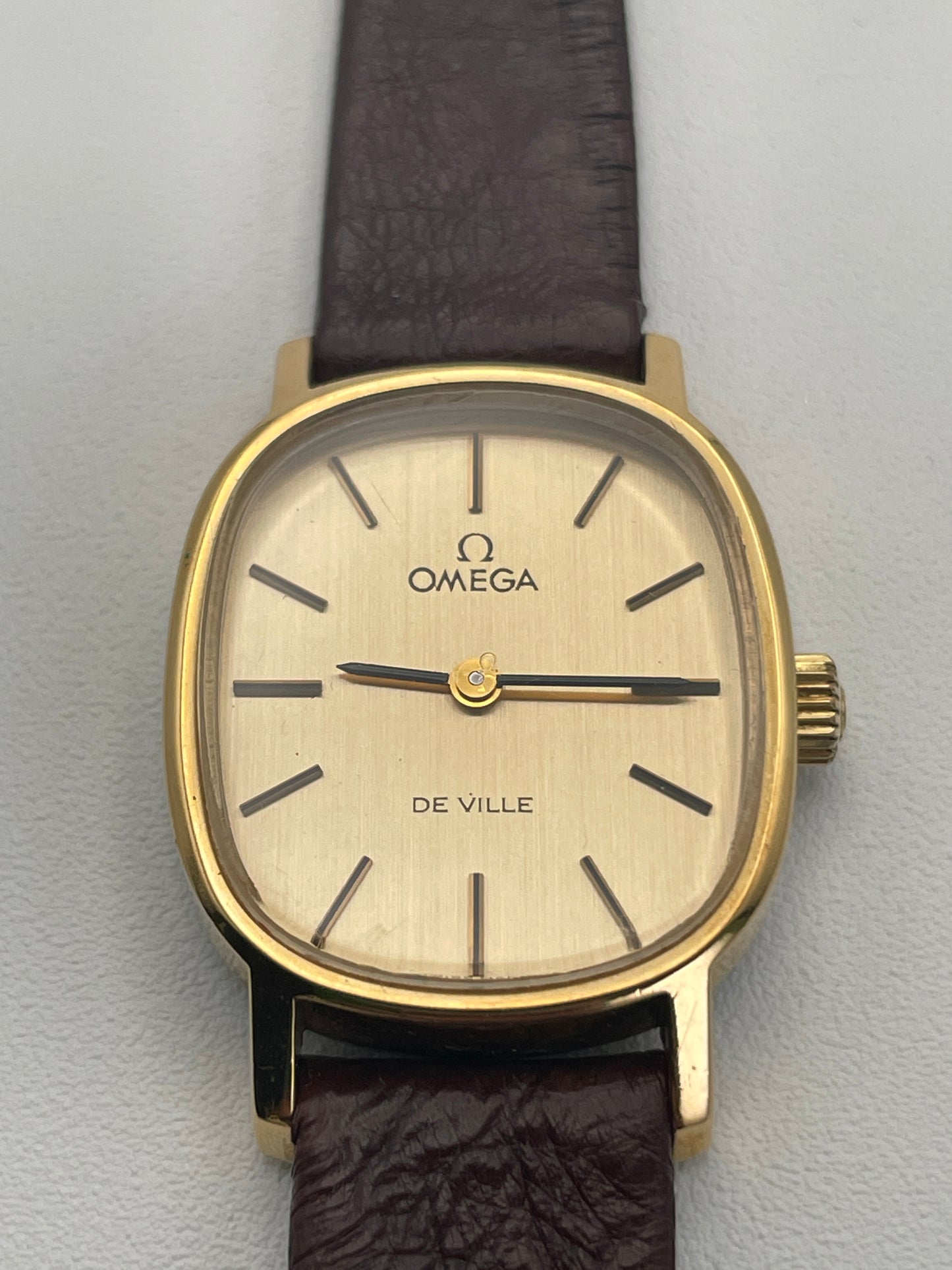 Close-up of the Omega De Ville 511.0509 watch dial, showcasing the gold case, minimalist dial, and brown leather strap.