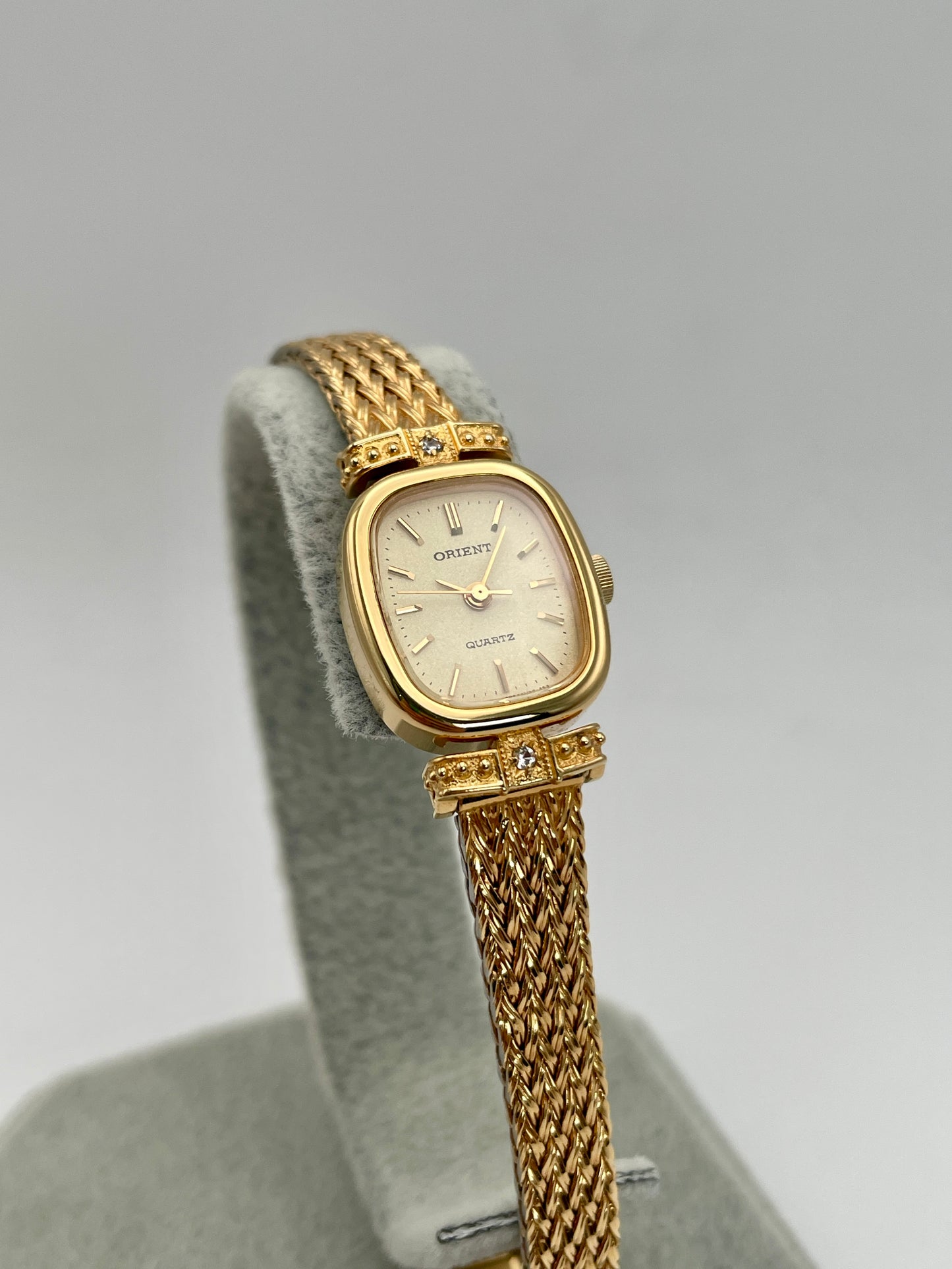 Front view of Orient Vintage Women's Watch in gold with champagne dial and diamond accents on a display stand.