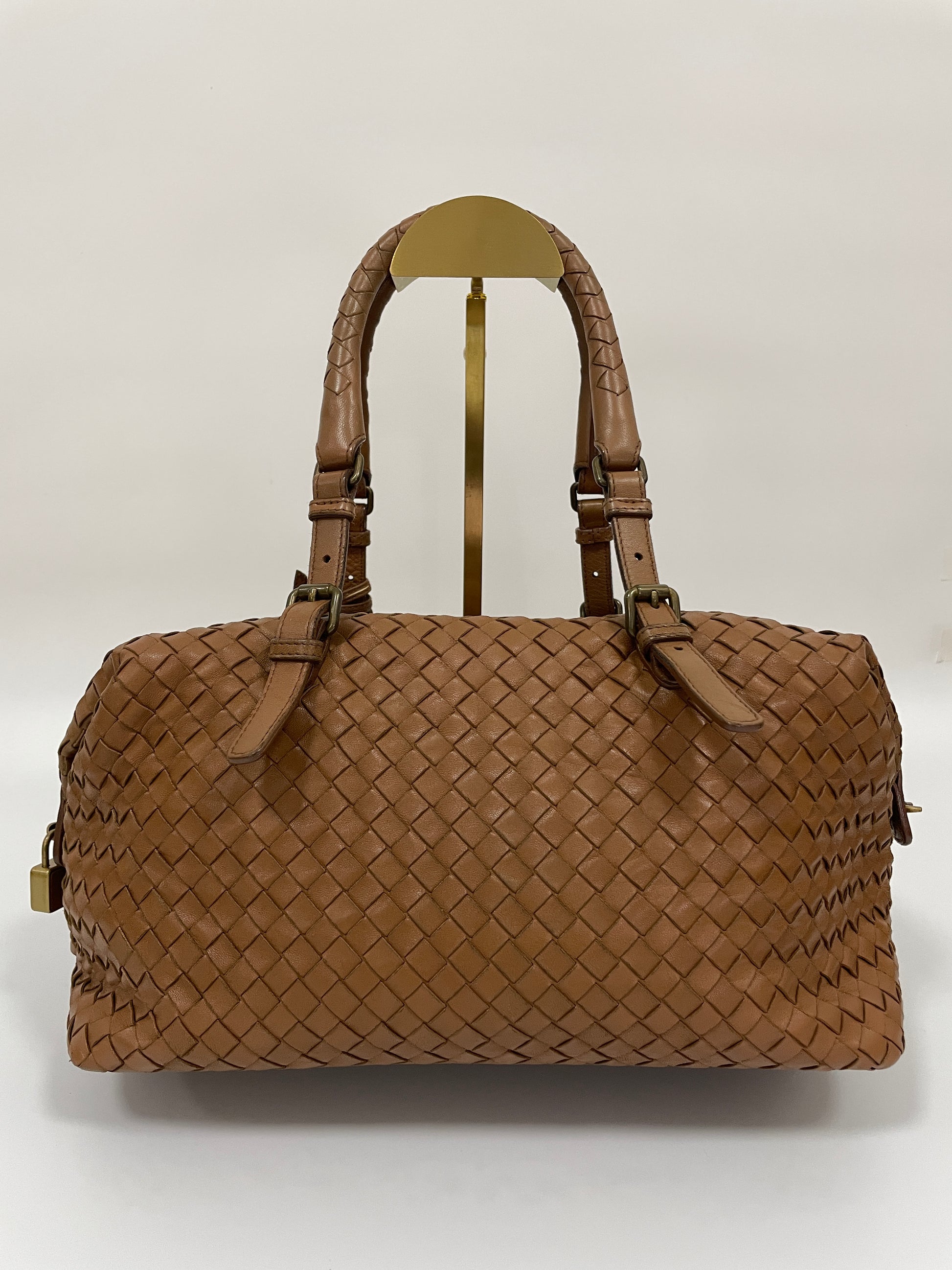 Rear view of a Bottega Veneta Intrecciato Montaigne bag in brown leather with dual handles and brass hardware.