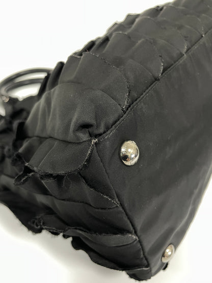 Close-up view of the corner of Prada Tessuto Ruffle Bag in black nylon, featuring protective silver-tone studs.