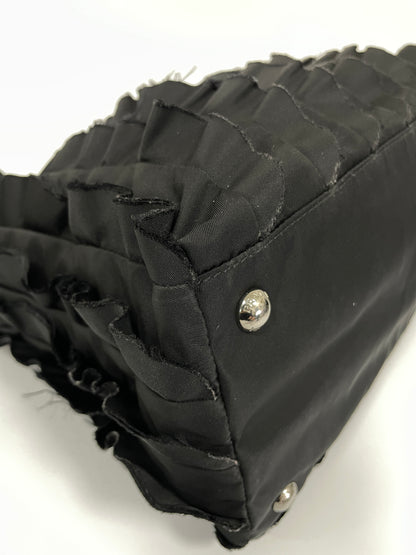 Close-up view of the corner of Prada Tessuto Ruffle Bag in black nylon, featuring protective silver-tone studs.