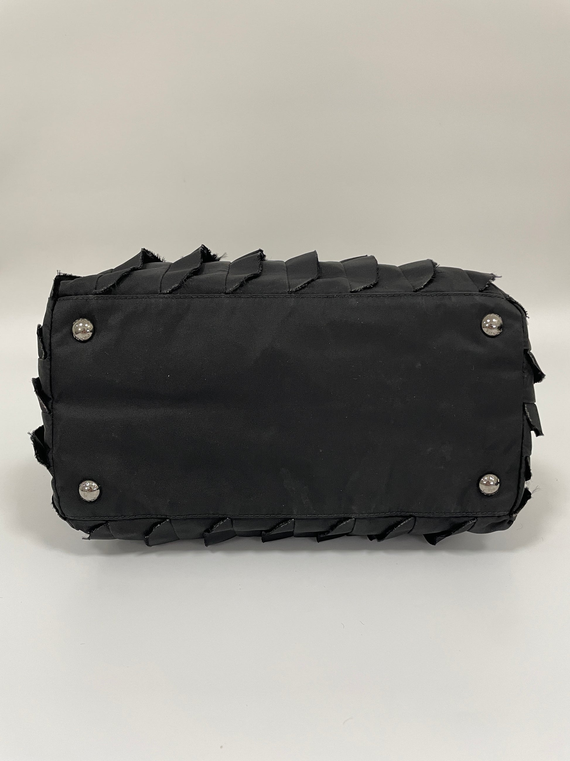 Bottom view of Prada Tessuto Ruffle Bag in black nylon with protective silver-tone studs.