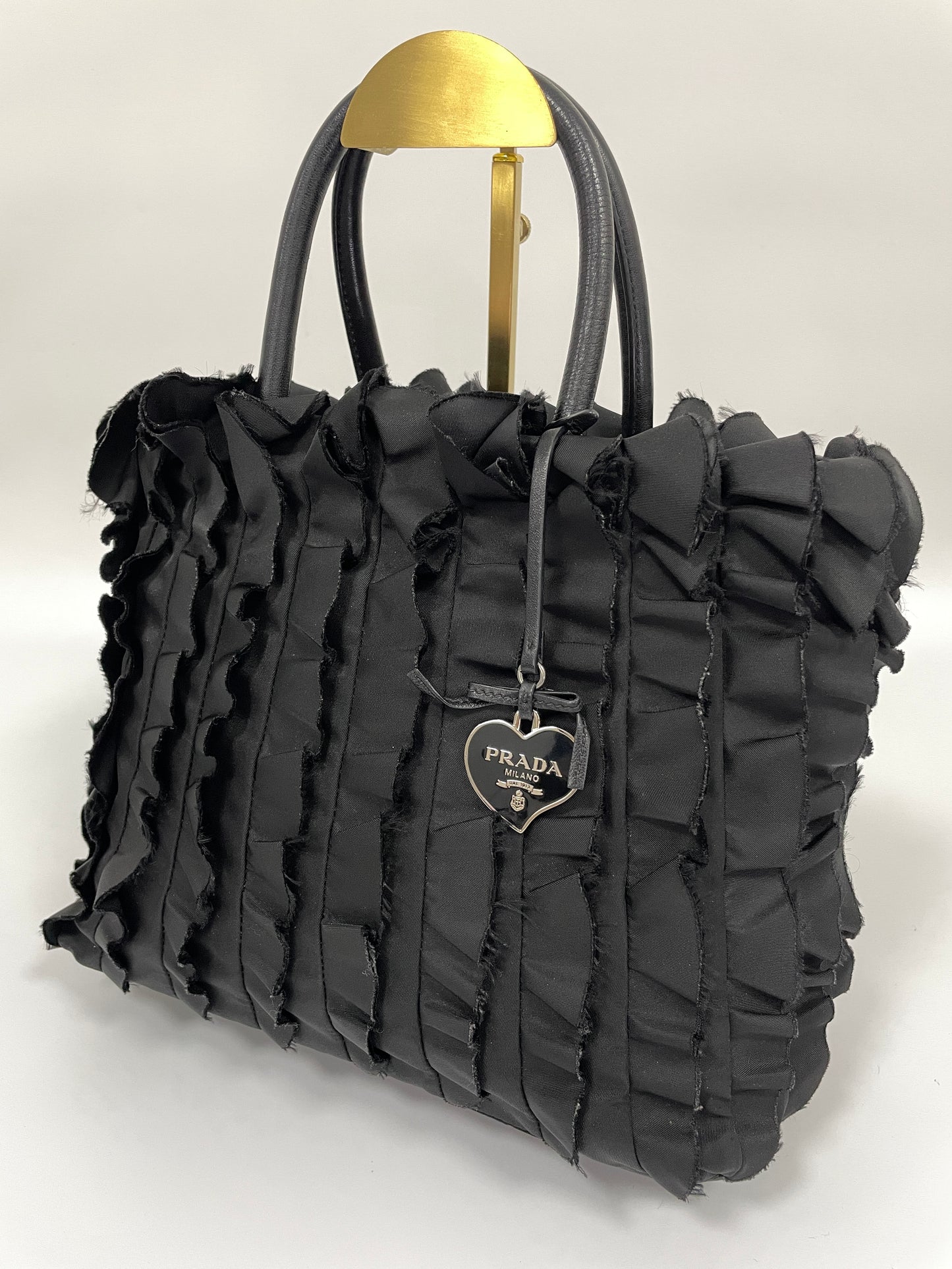 Diagonal front view of Prada Tessuto Ruffle Bag in black nylon, showcasing the ruffled texture and iconic Prada logo charm.