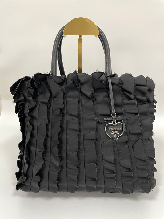 Front view of Prada Tessuto Ruffle Bag in black nylon with ruffled detailing and heart-shaped Prada logo charm.