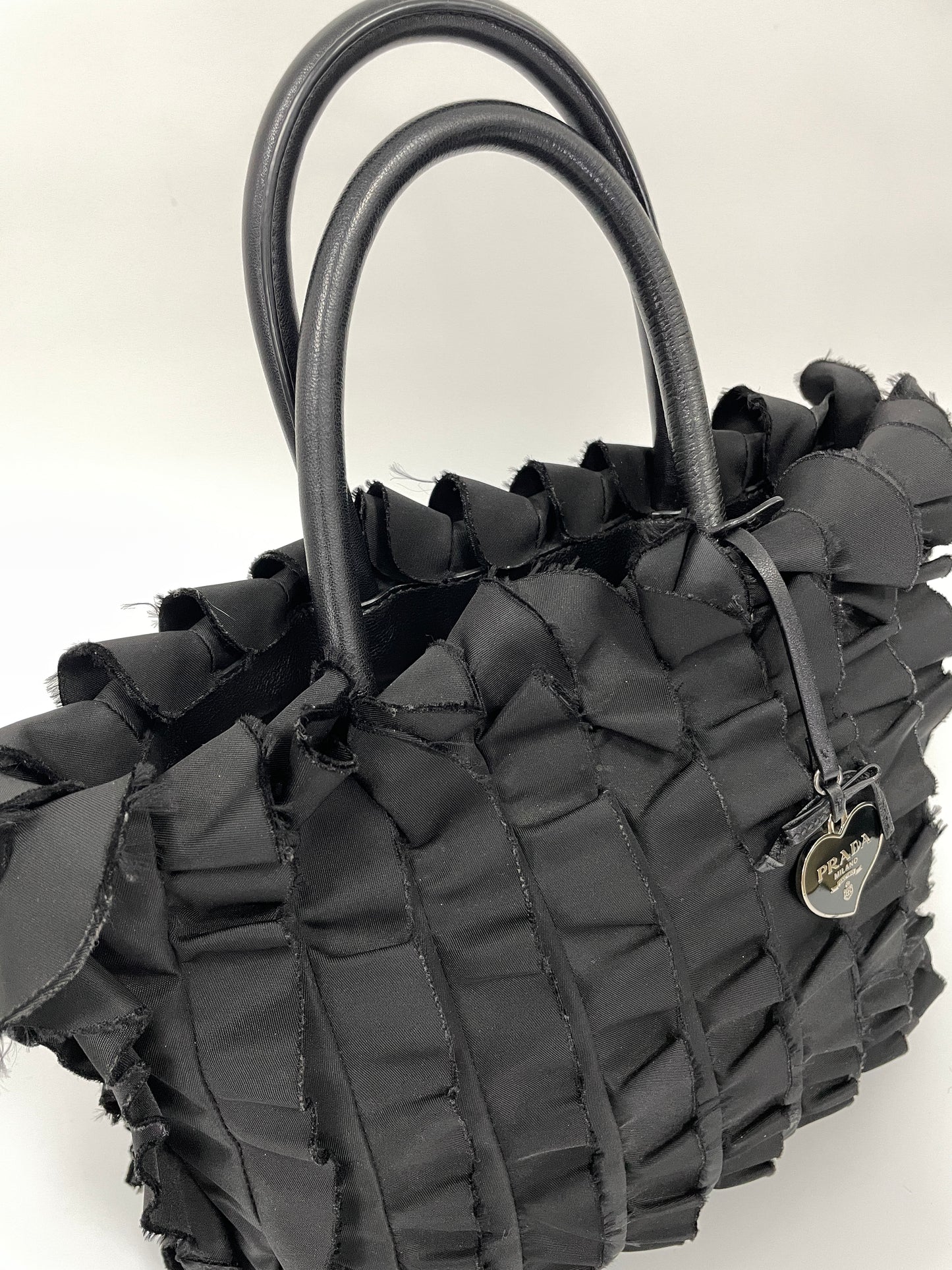 Angle view of the Prada Tessuto Ruffle Bag in black nylon showcasing its front detail and black leather handles.