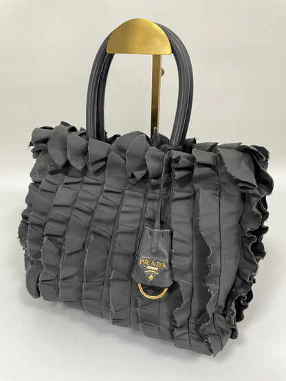 Angled view of Prada Tessuto Ruffle Bag in grey nylon showing ruffled texture and leather Prada logo tag.