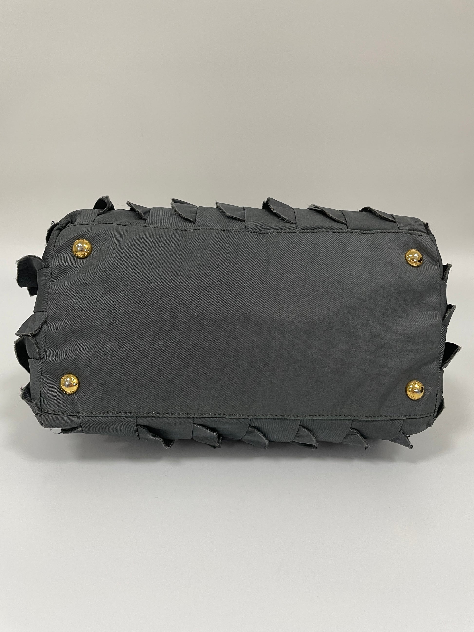 Bottom view of the Prada Tessuto Ruffle Bag in grey nylon featuring gold-tone protective studs.