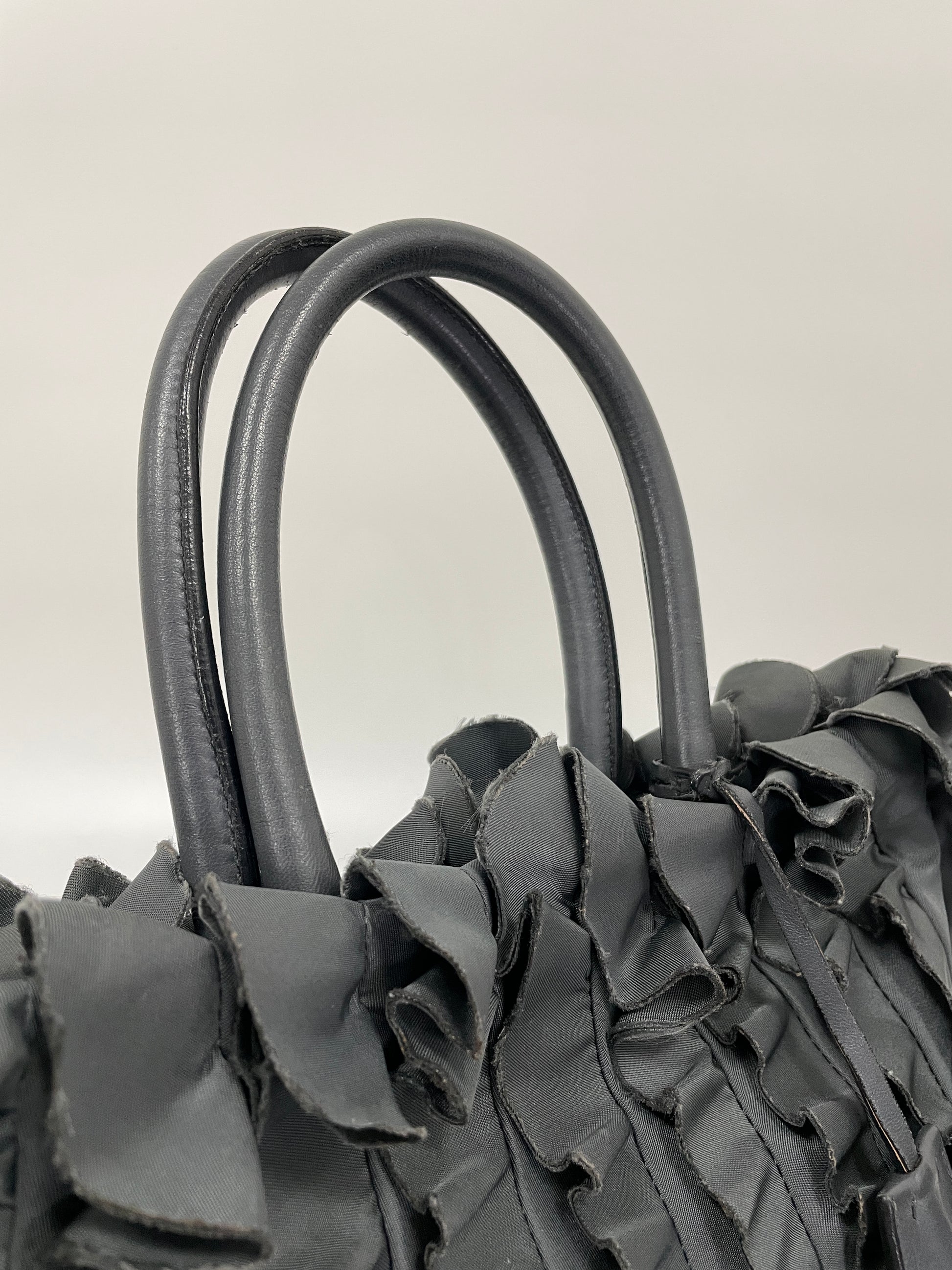 Close-up of the double leather handles of the Prada Tessuto Ruffle Bag in grey nylon.