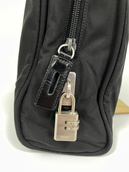 Close-up of the Prada silver combination lock attached to the zipper of the Prada Tessuto Tote Bag in black nylon, adding an extra layer of security.