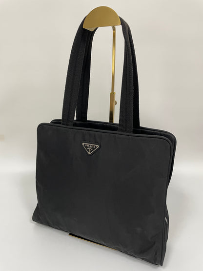 Front angled view of the Prada Tessuto Tote Bag in black nylon with dual top handles and the signature triangular Prada logo plate.