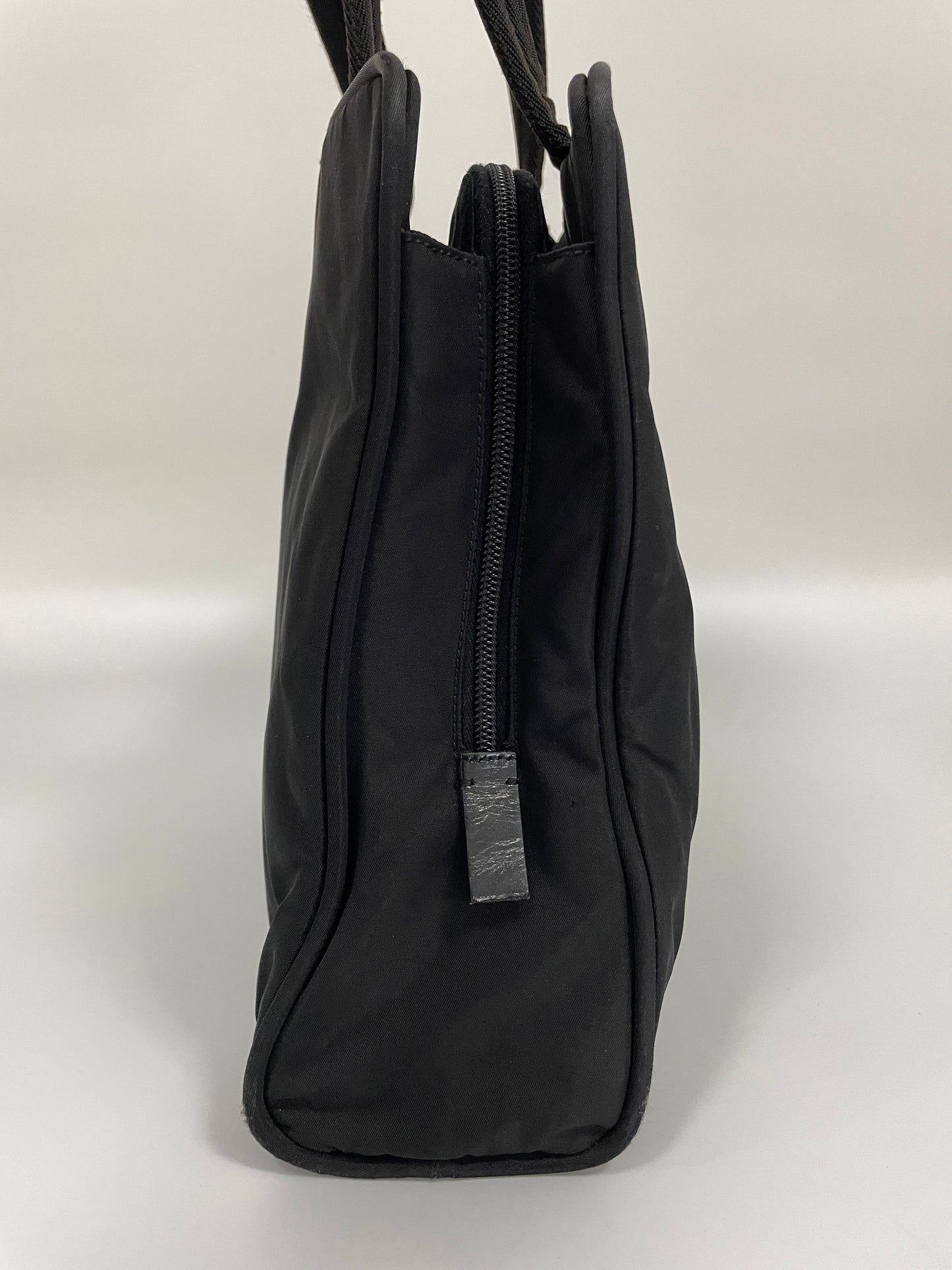 Side view of the Prada Tessuto Tote Bag in black nylon, showing the slim profile with a zipper closure.