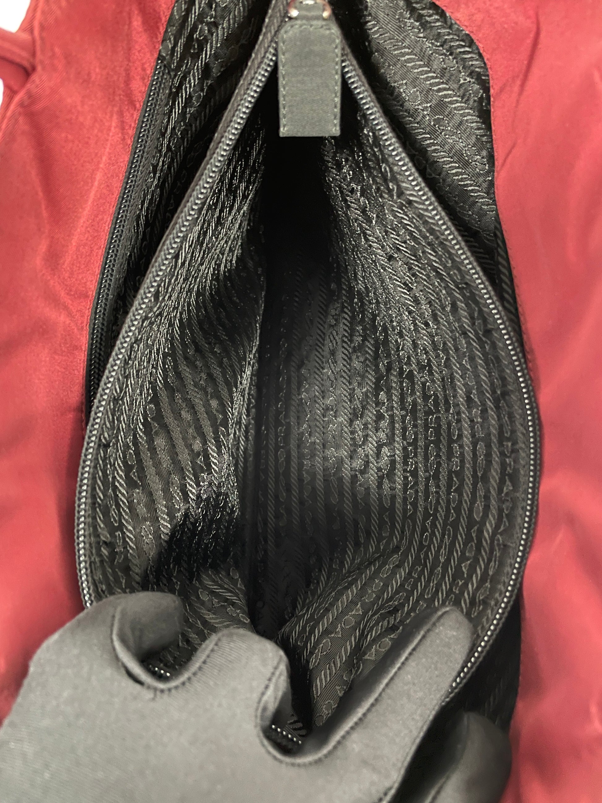 View of the inside of the pocket of the Prada Tessuto Tote Bag in red nylon displaying the spacious black fabric lining.