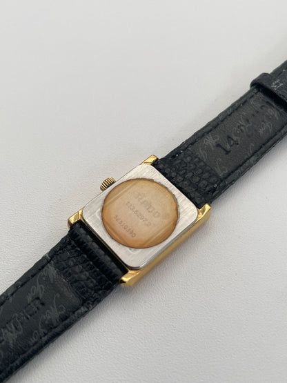 Vintage Rado Tank watch in gold case with a rectangular dial and black leather strap, caseback view showing model details.