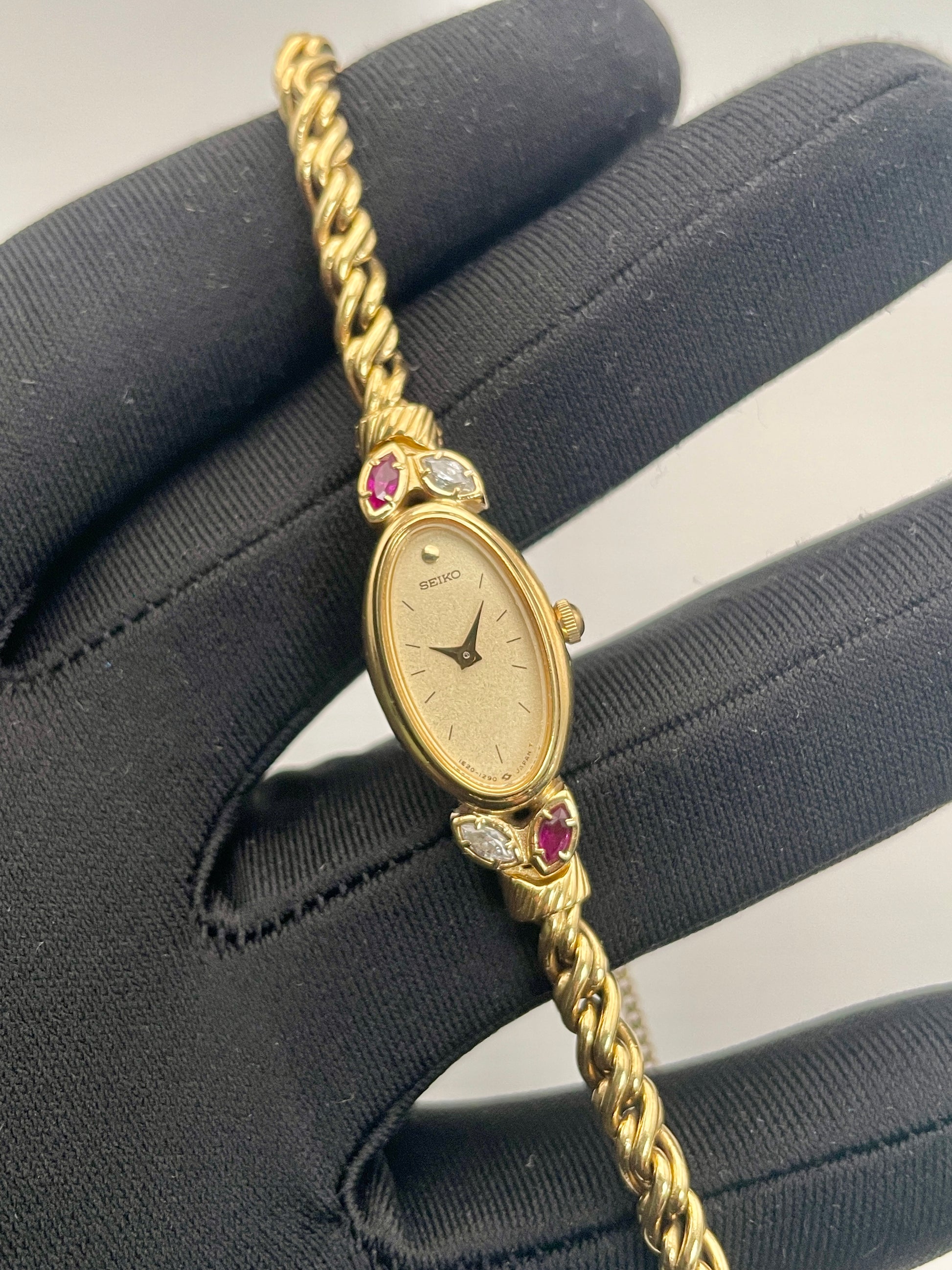 Close-up view of Seiko 1E20-5760 vintage women's gold watch with ruby and diamond-inspired detailing.