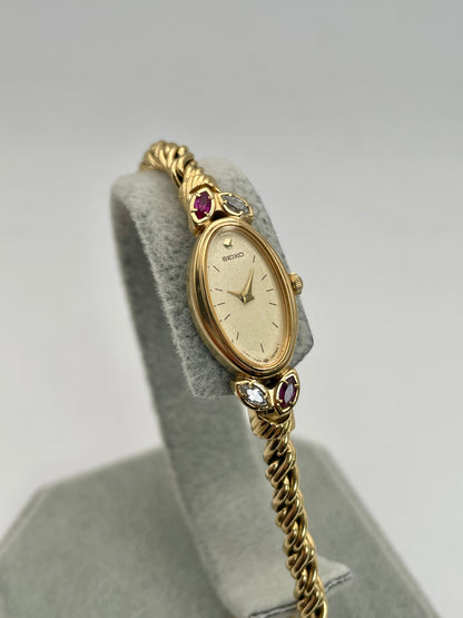 Main view of Seiko 1E20-5760 vintage women's watch in gold showcasing oval dial and gemstone accents.