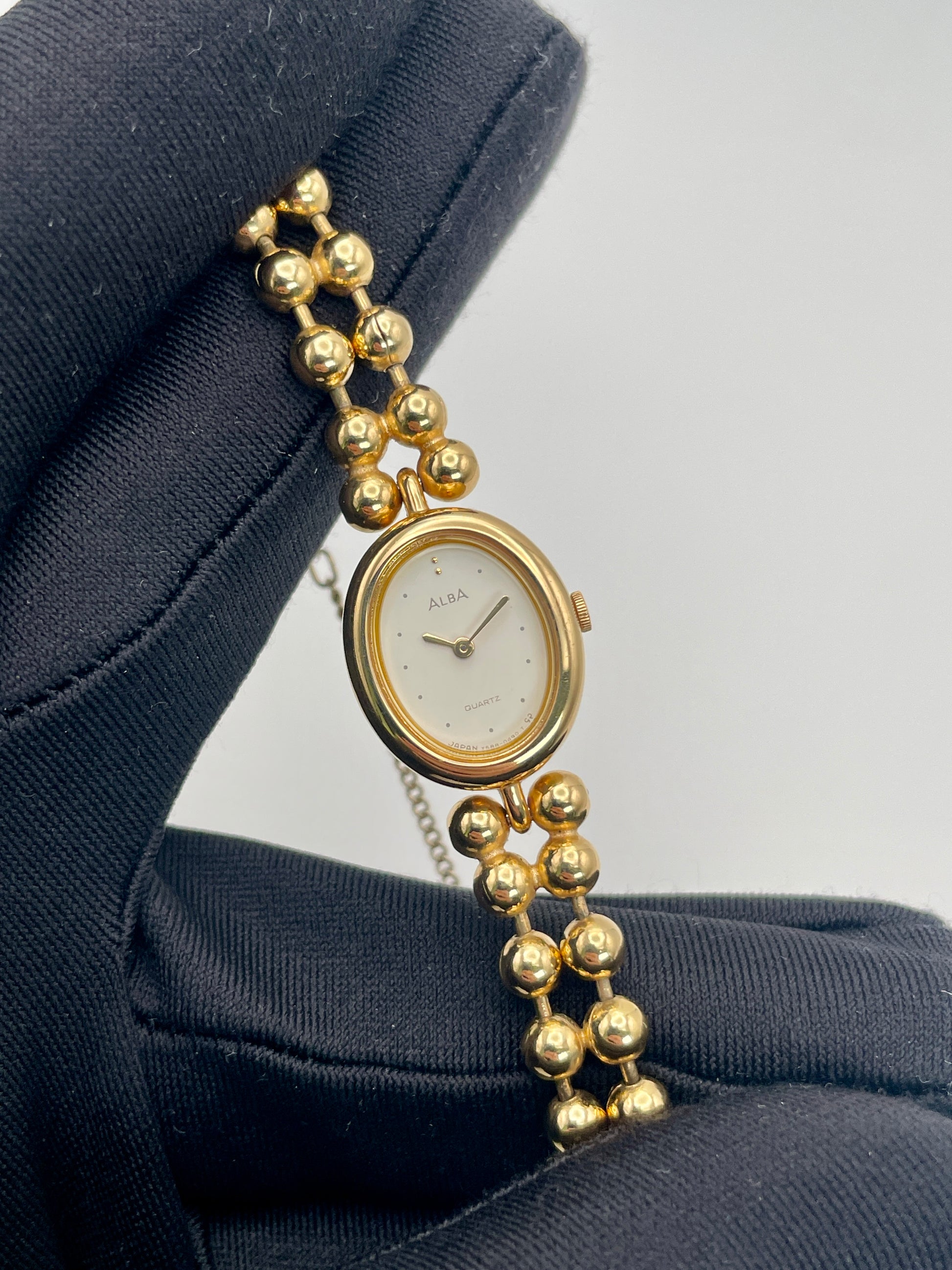 Close-up view of Seiko Alba Y588-5180 vintage gold watch highlighting white dial and gold bracelet.