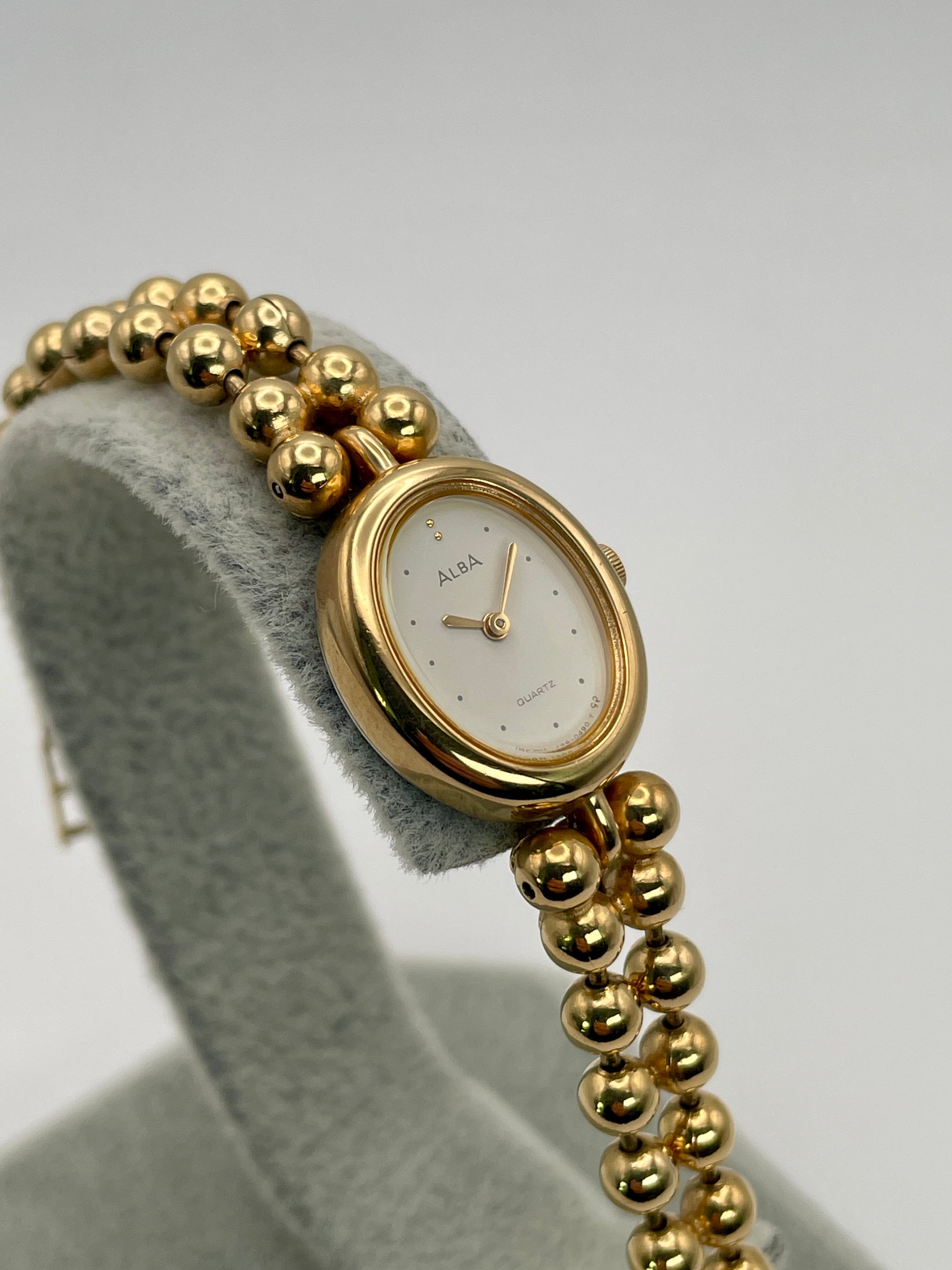 Front view of Seiko Alba Y588-5180 vintage women's watch in gold with white dial and bead bracelet.