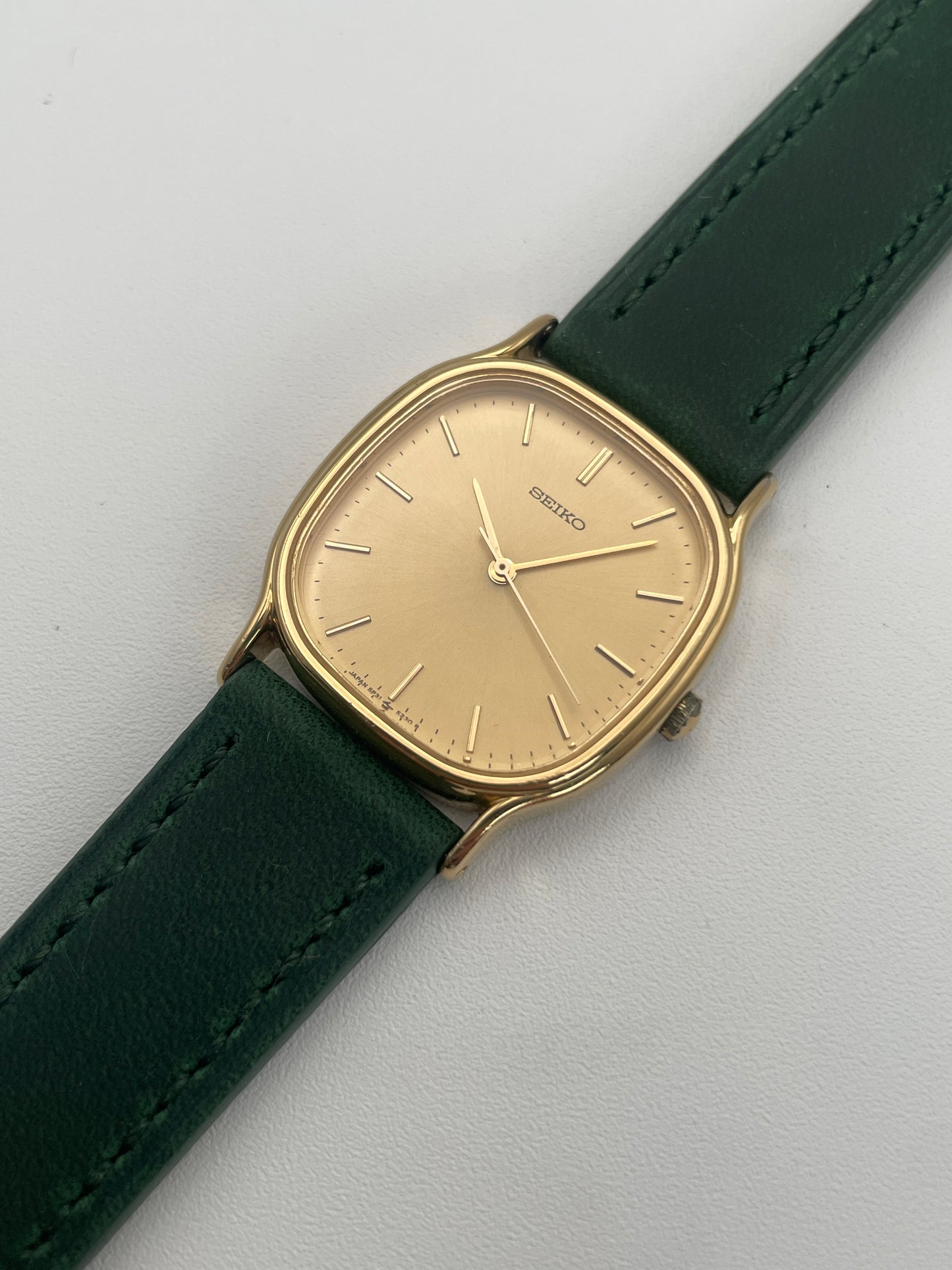 Diagonal view of Seiko Chariot in gold-tone with minimalistic dial and green leather strap.