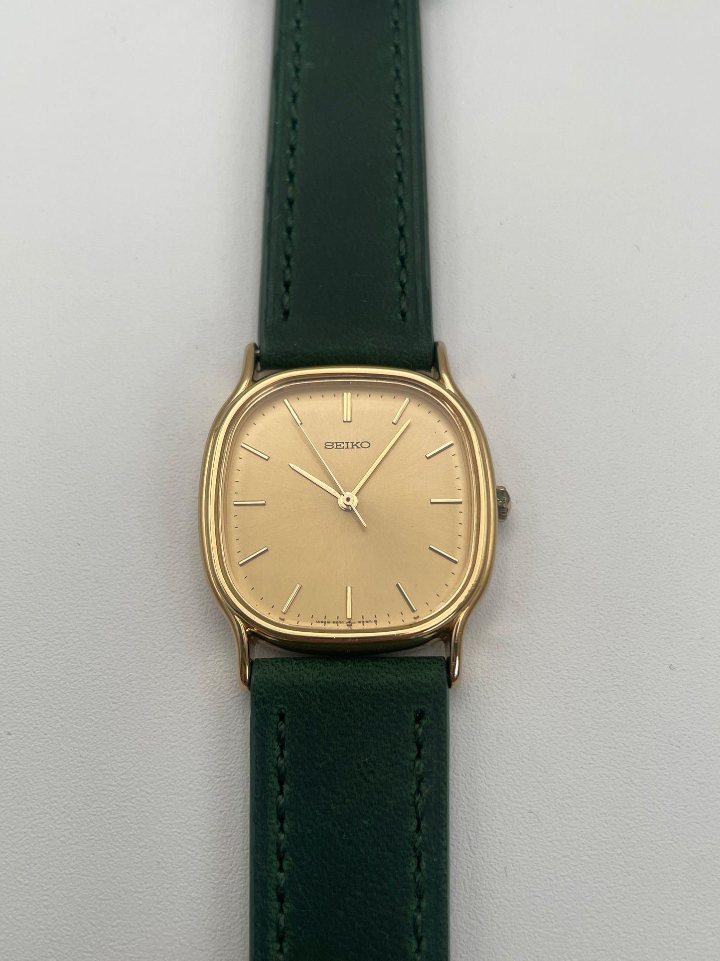 Front view of Seiko Chariot in gold-tone with minimalistic dial and green leather strap.