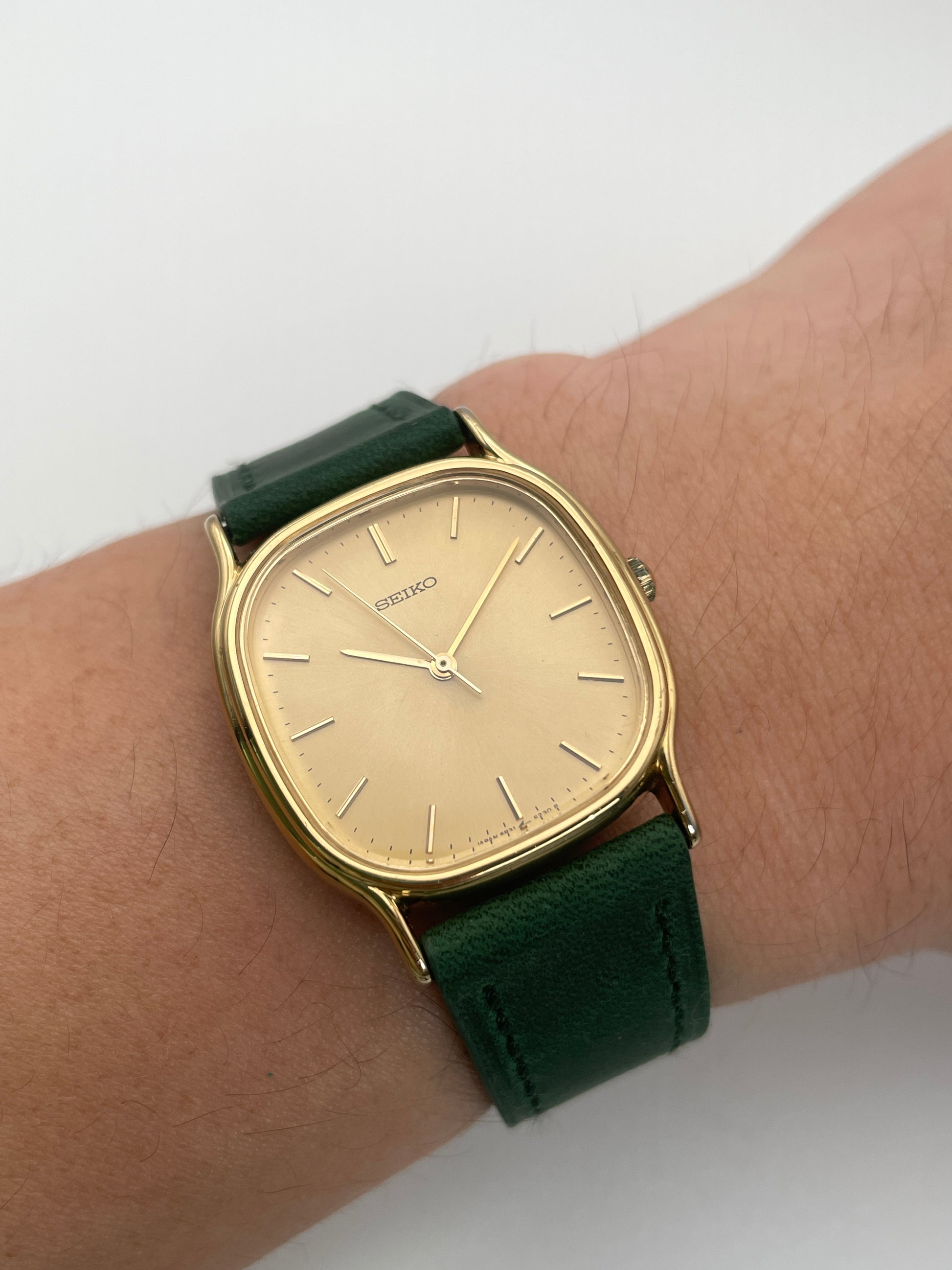 Wrist shot view of Seiko Chariot in gold-tone with green leather strap on wrist.