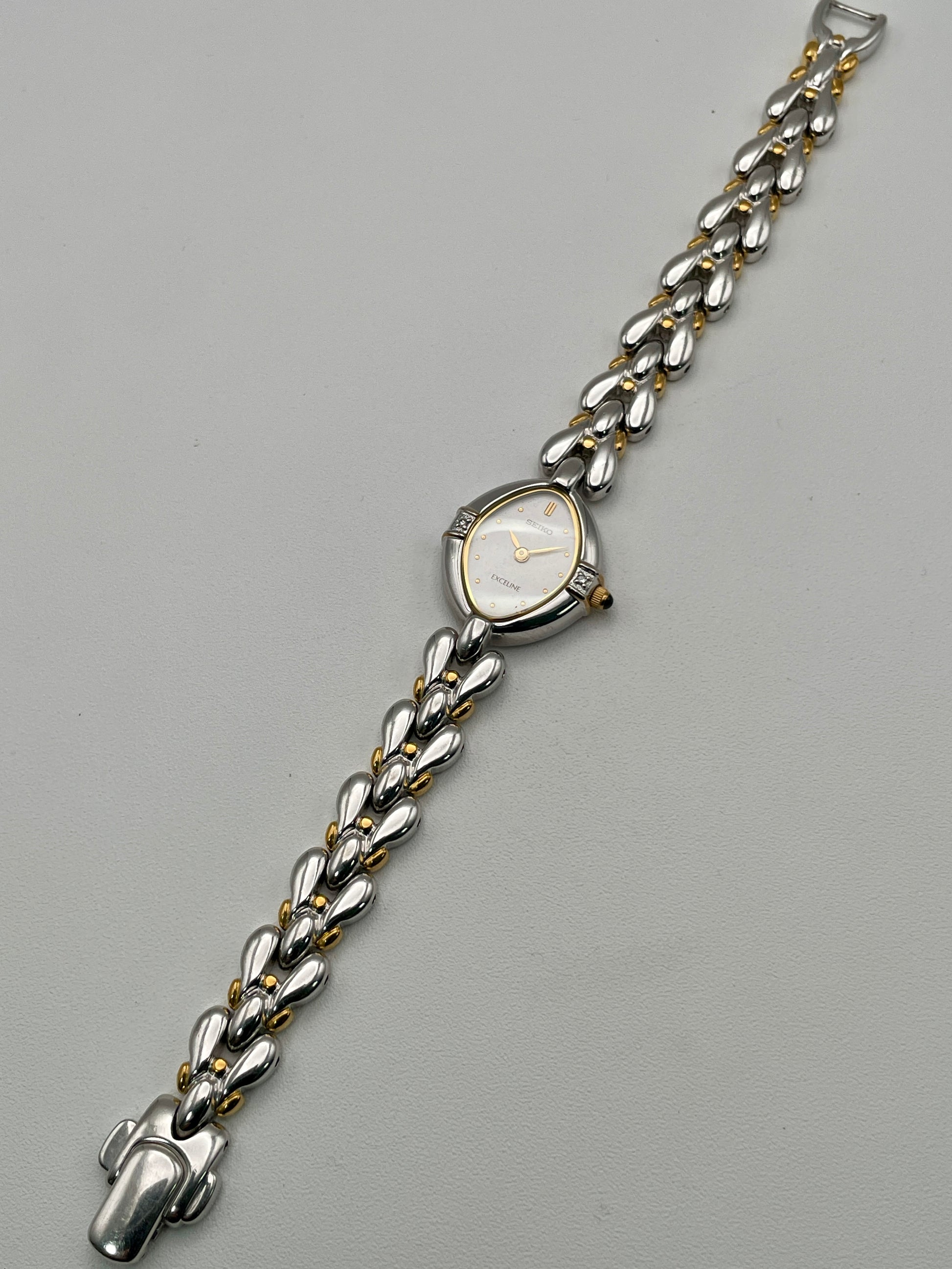 Full watch view laid flat, displaying the entire bracelet and teardrop case
