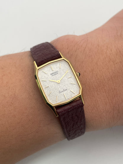 Seiko Exceline Decagon Ladies Watch in gold on the wrist, showing its size and elegant burgundy leather strap.